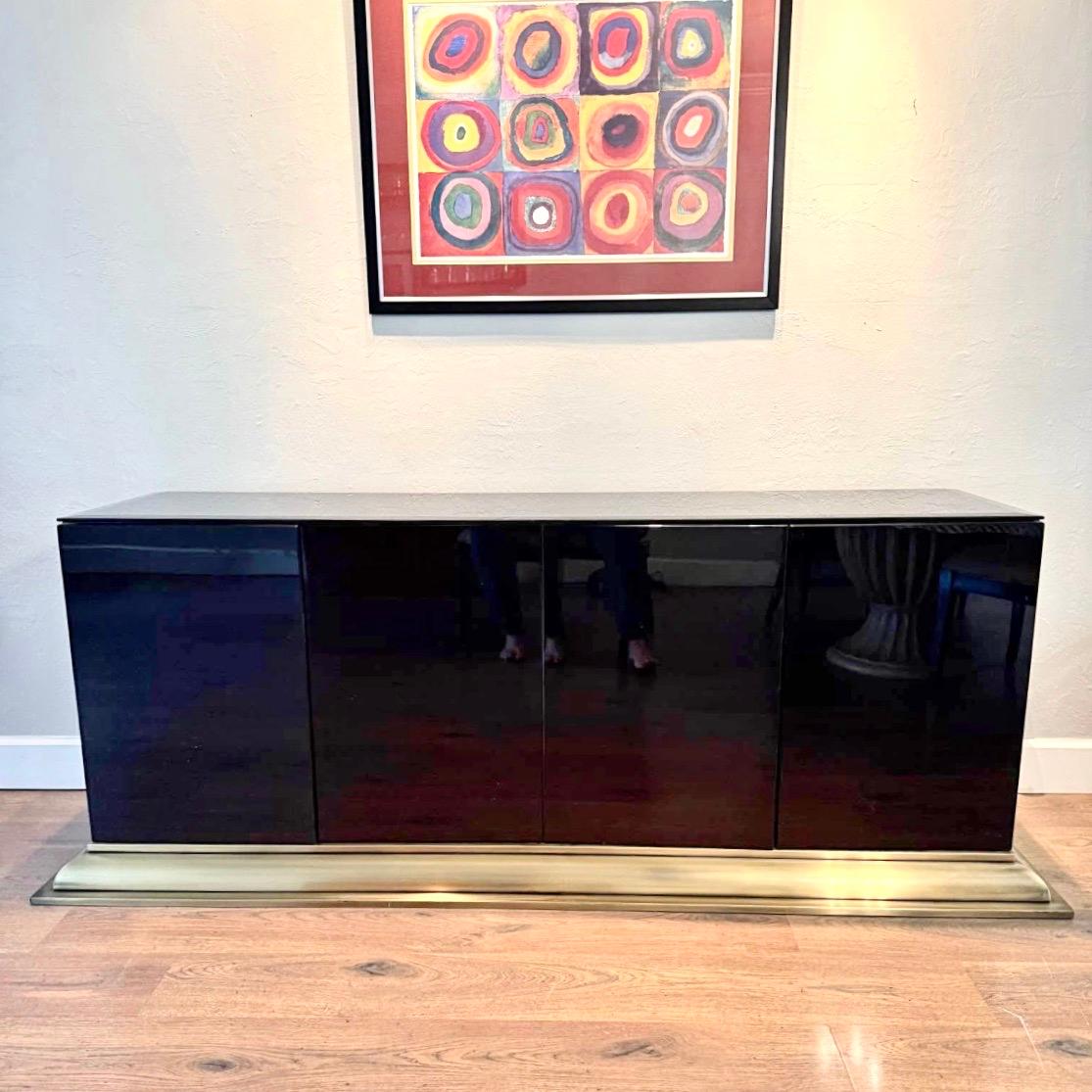 Mobile buffet a credenza elegante e minimalista con linee pulite e assenza di ferramenta a vista. Rivestita interamente in vetro nero, quattro ante, due armadietti con ripiano singolo, modanatura in ottone lungo la base.
La custodia nera misura 72 x