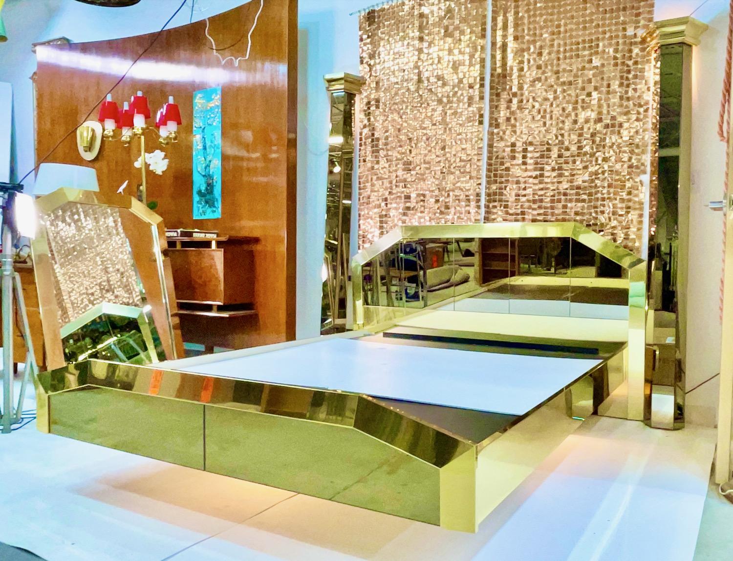 We actually have TWO of these beds available.
Jaw dropping queen size two poster floating platform bed clad in polished brass and bronzed mirrored glass designed by O. B. Solie for Ello Furniture Manufacturing Co. from the 