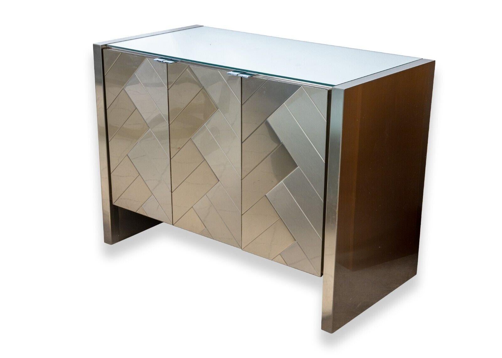 An Ello contemporary modern small chevron credenza. These beautiful contemporary credenzas feature a beautiful choice of materials, gorgeous design, and plenty of functional storage space. Each of these identical pieces feature a glass top, brushed