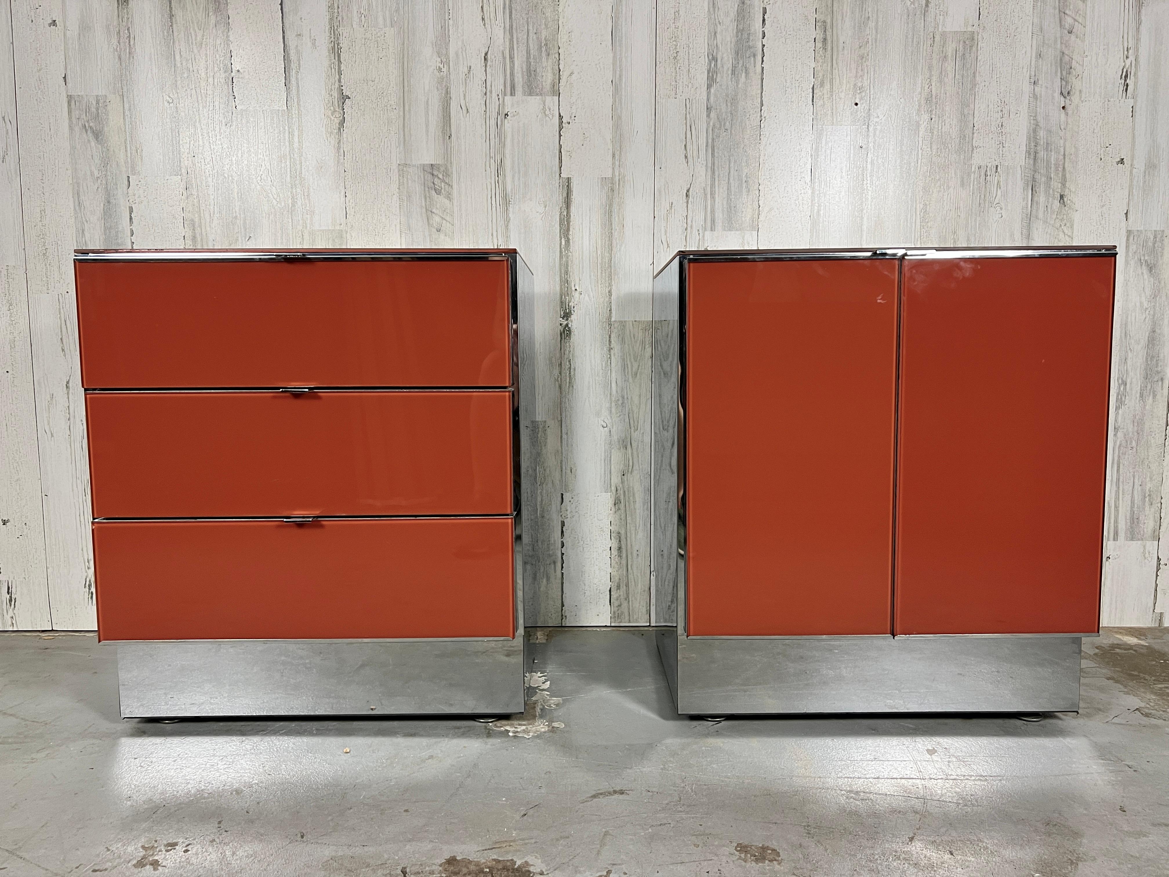 Ello Lacquered glass and chrome nightstands. Burnt Orange lacquered glass with shiny chrome, sides, trim, and handles. One of the nightstands has drawers and the other has doors.