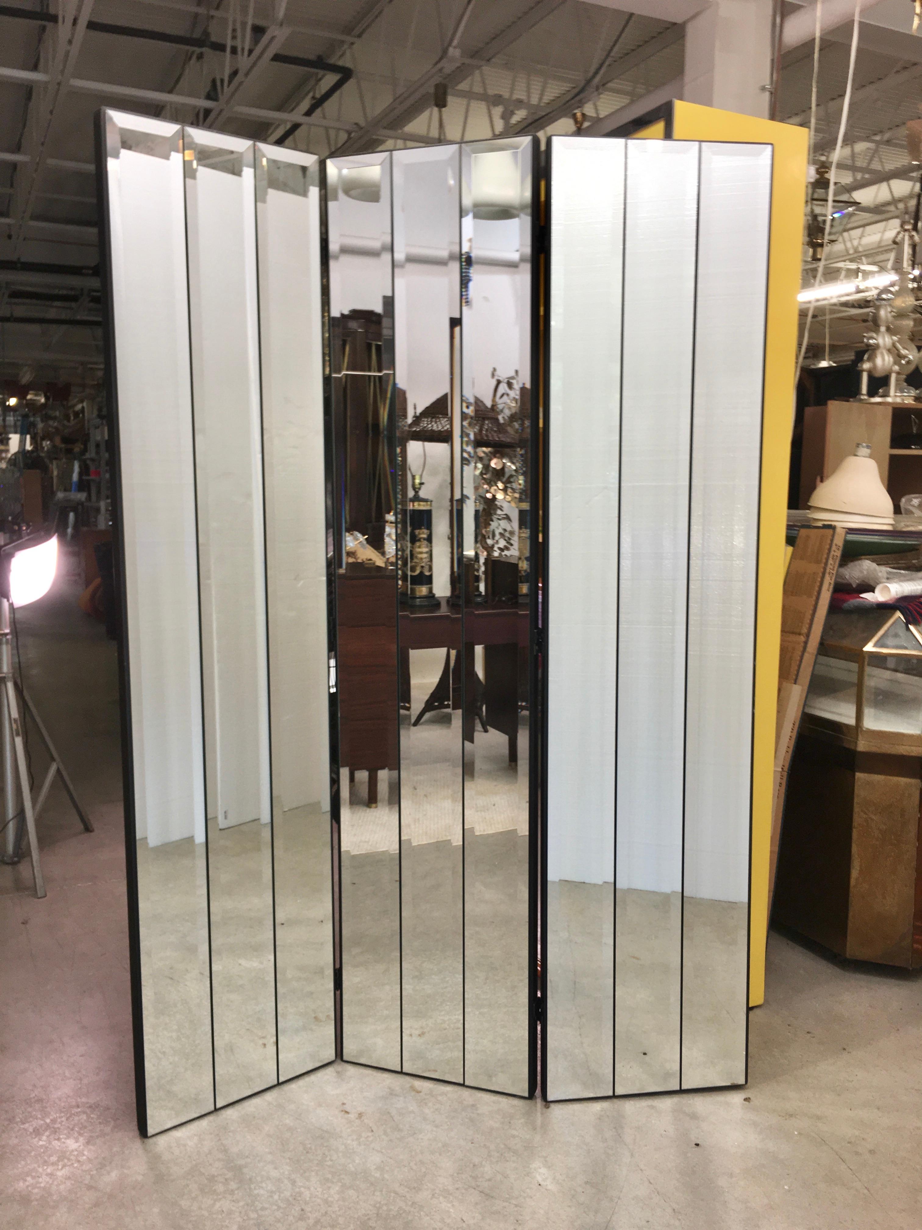 Tall and solid three-panel hinged folding paravent by Ello furniture, circa 1975. Each 18 inch wide panel is applied with three elongated beveled mirrored glass. The panels are ebonized solid oak. Last two photos demonstrate the range of