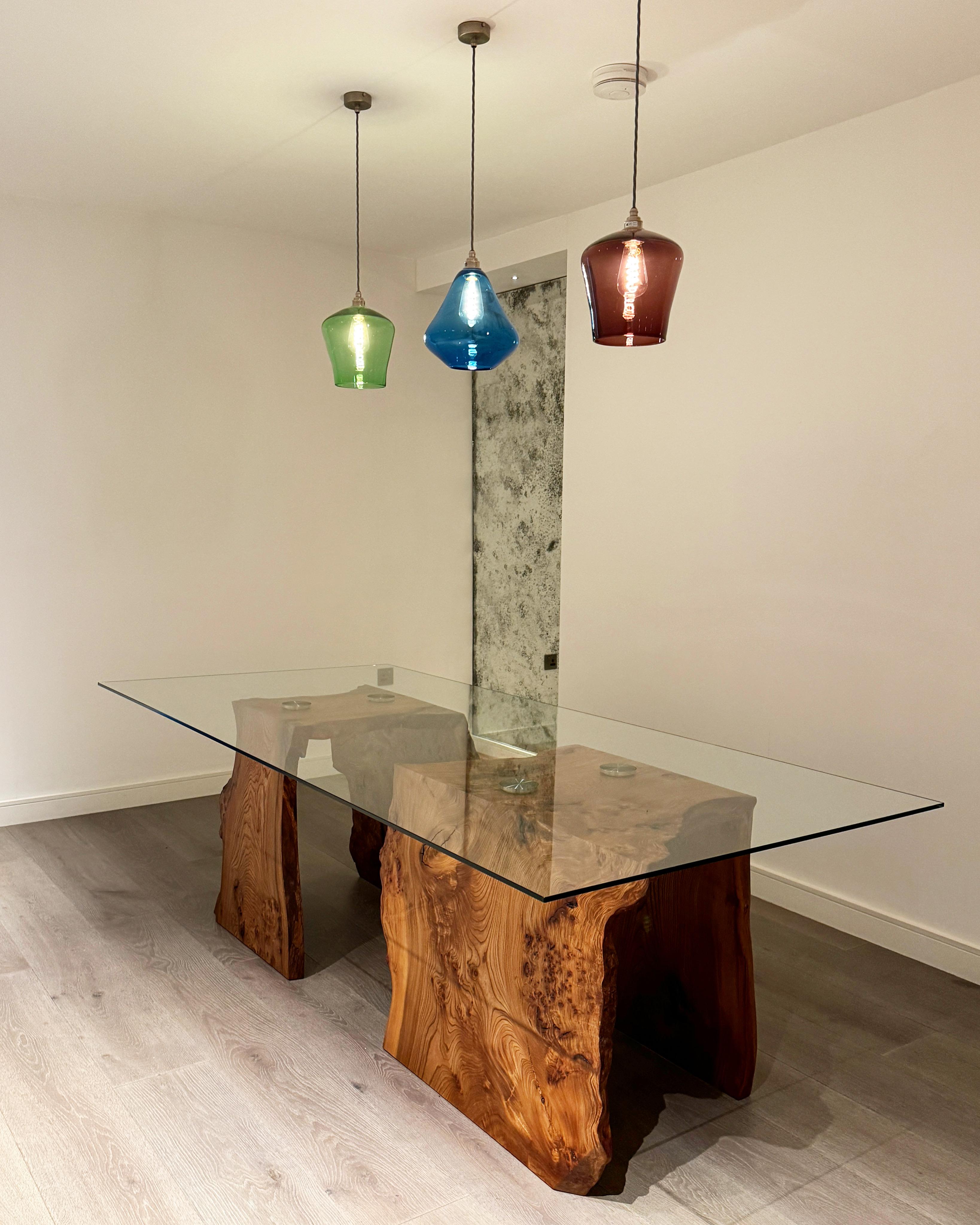 Utilizando una variante muy especial de la madera de olmo (burr Elm), cada una de las dos bases de mesa comienza su vida como una única tabla de gran tamaño. Luego se cortan en tres piezas en ángulos de 45 grados y se vuelven a unir para crear el