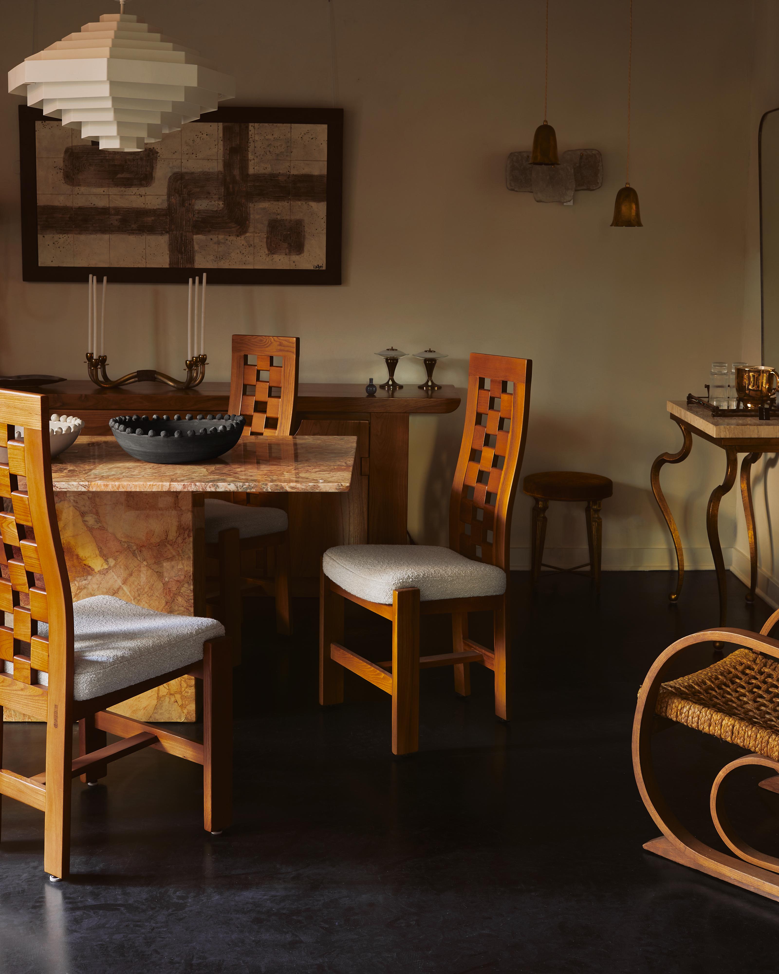 A French dining chair from the 1970s, attributed to Maison Regain. The solid elm frame rests on angular, block legs with a central stretcher anchoring the design, while the back features a subtly curved checkered motif. The seat has been expertly