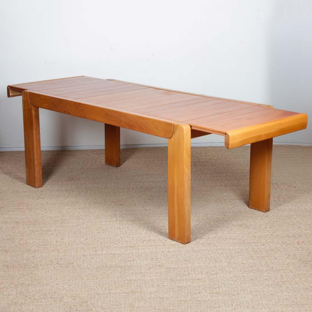 This solid elm dining table was produced by Maison Regain in the 1970s. It opens in the middle to expand thanks to an integrated extension leaf. It measures 58 cm. This piece is in a good vintage condition.