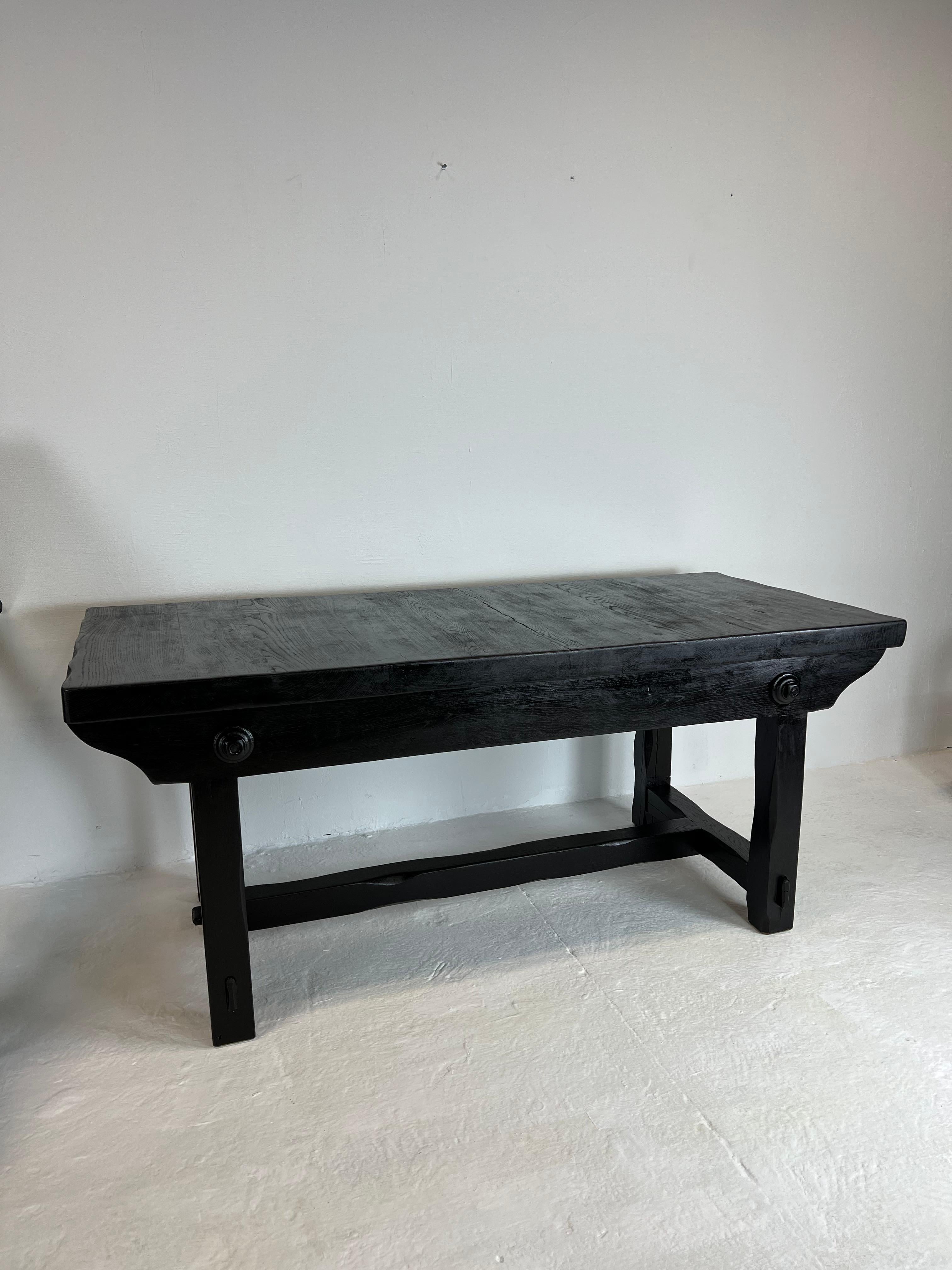 Very nice solid elm dining table from the 1950s with a thick top, accompanied by its two benches. It is a unique piece made by a craftsman on the basis of an old press. It has been completely sanded then lacquered in matte black to give it a