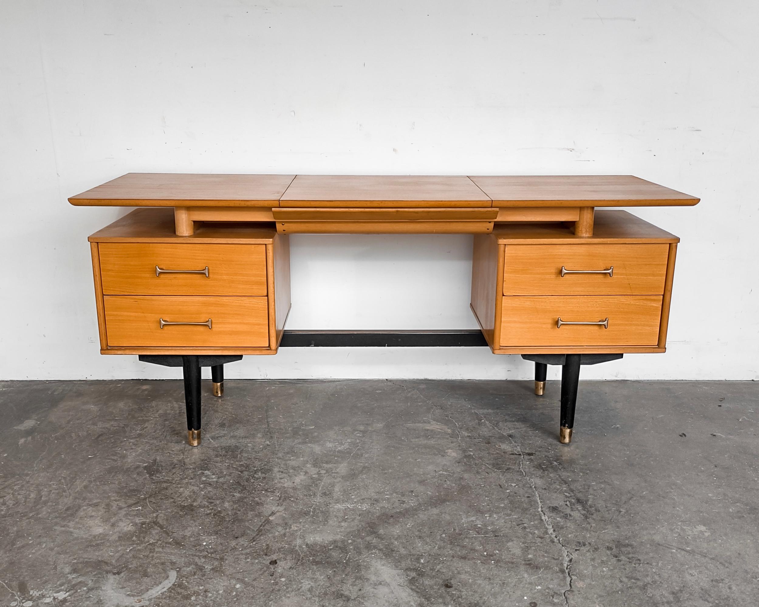 Flip-top elm wood vanity desk by Milo Baughman for Drexel. Painted black base with brassy hardware and four drawers. No chips to mirror and all drawers slide well. Finished on back.

Measures: 60” L
20.5” D
27