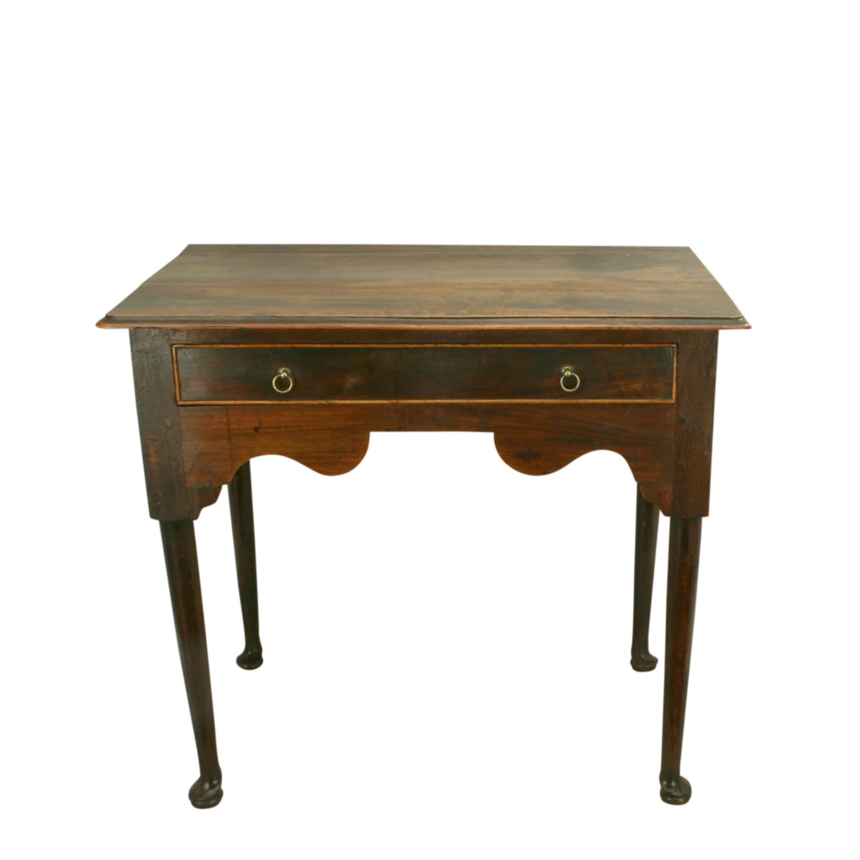 Elm low boy.
A good quality elm lowboy, side table. The rectangular top with round corners and edged moulding. One central drawer with cockbeading and two brass drop ring handles. The side table with shaped wavy apron and four turned legs