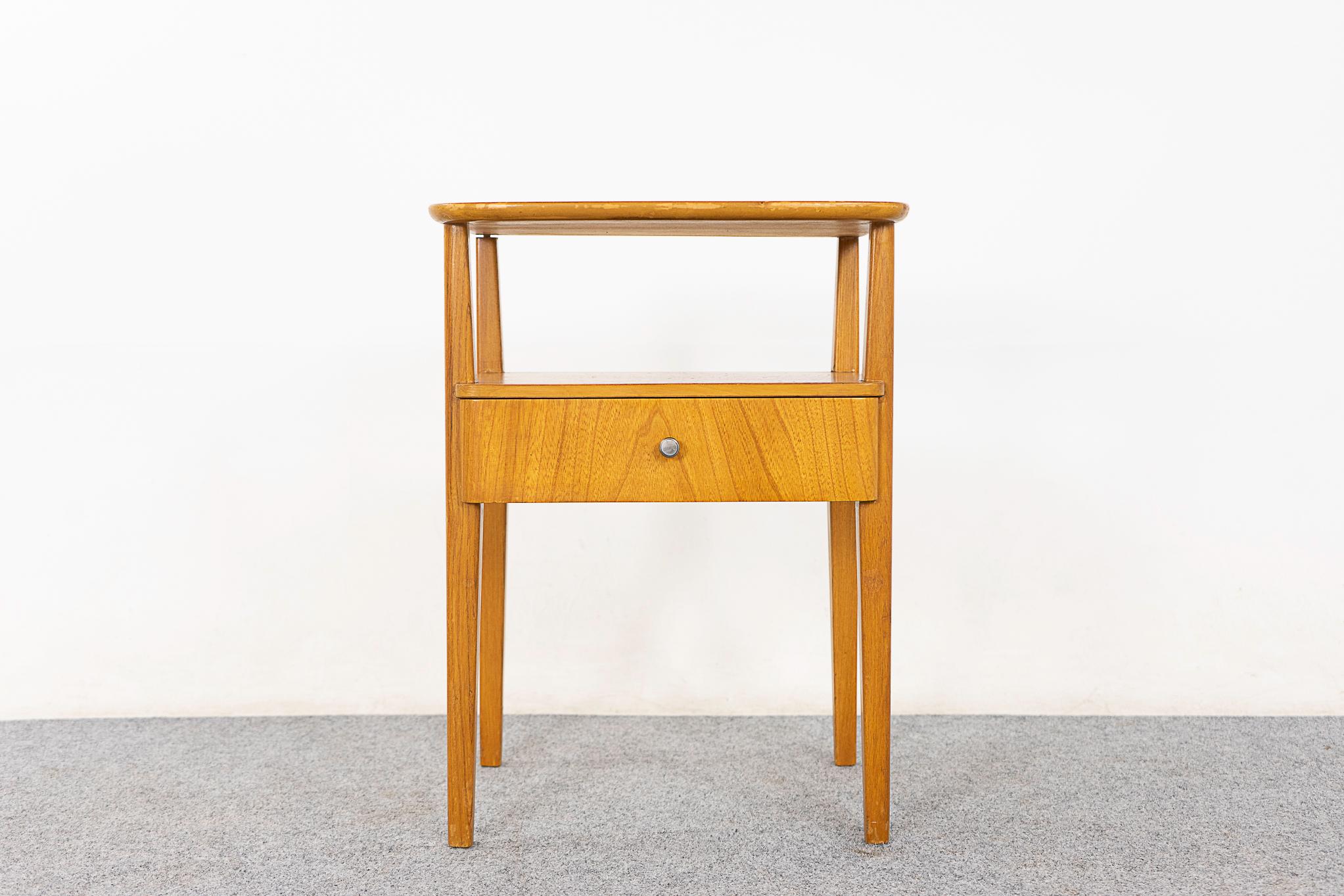Elm mid-century modern bedside table, circa 1960's. Lovely veneered case and drawer face, tapered legs and sweet little metal pull! 

Unrestored item with option to purchase in restored condition for an additional $150 USD. Restoration includes: