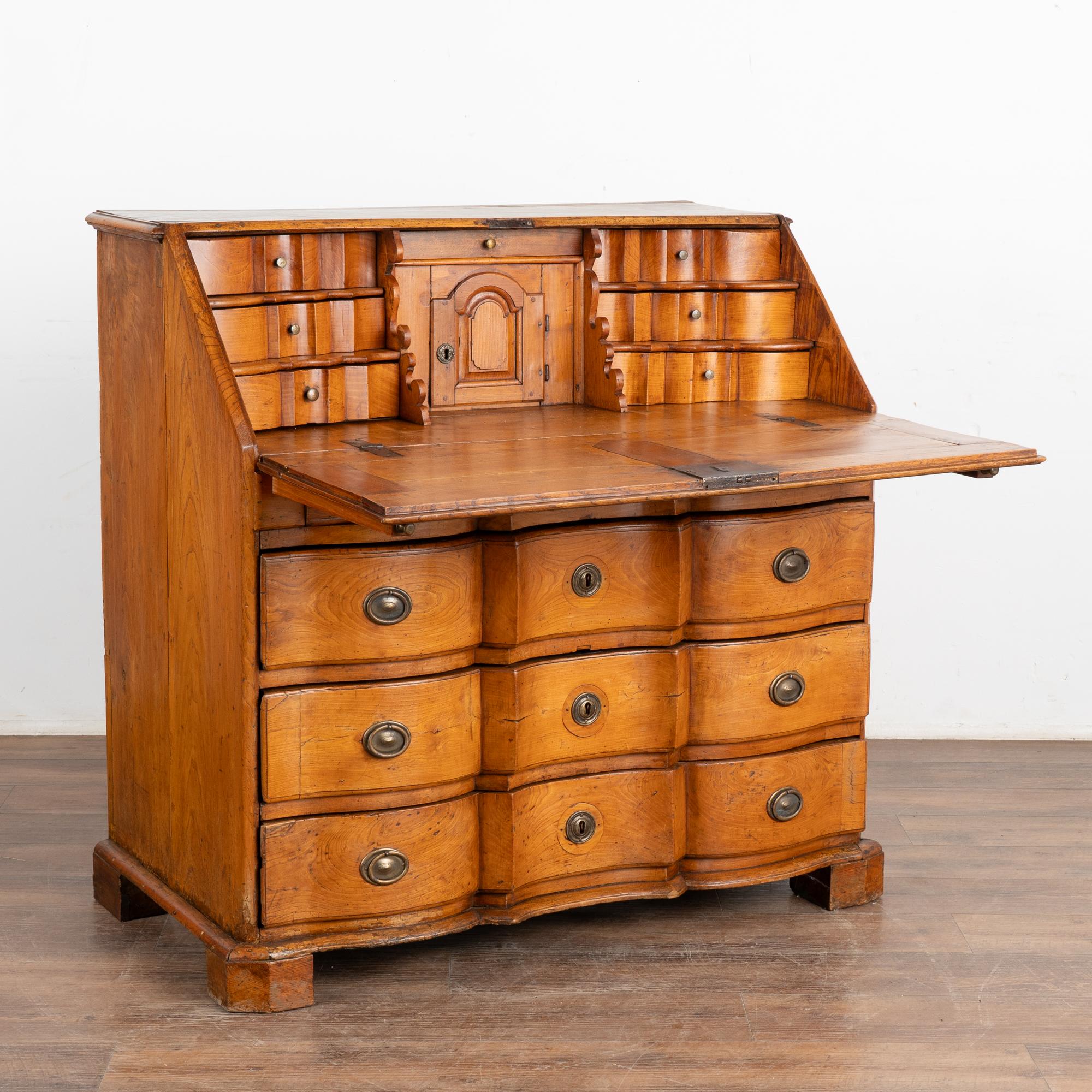 The warm patina of the aged elm glows with life in this lovely rococo secretary or bureau with striking inlaid double star pattern along desk front.
The interior 7 drawers and one central cubbie with petite door create an inviting interior work
