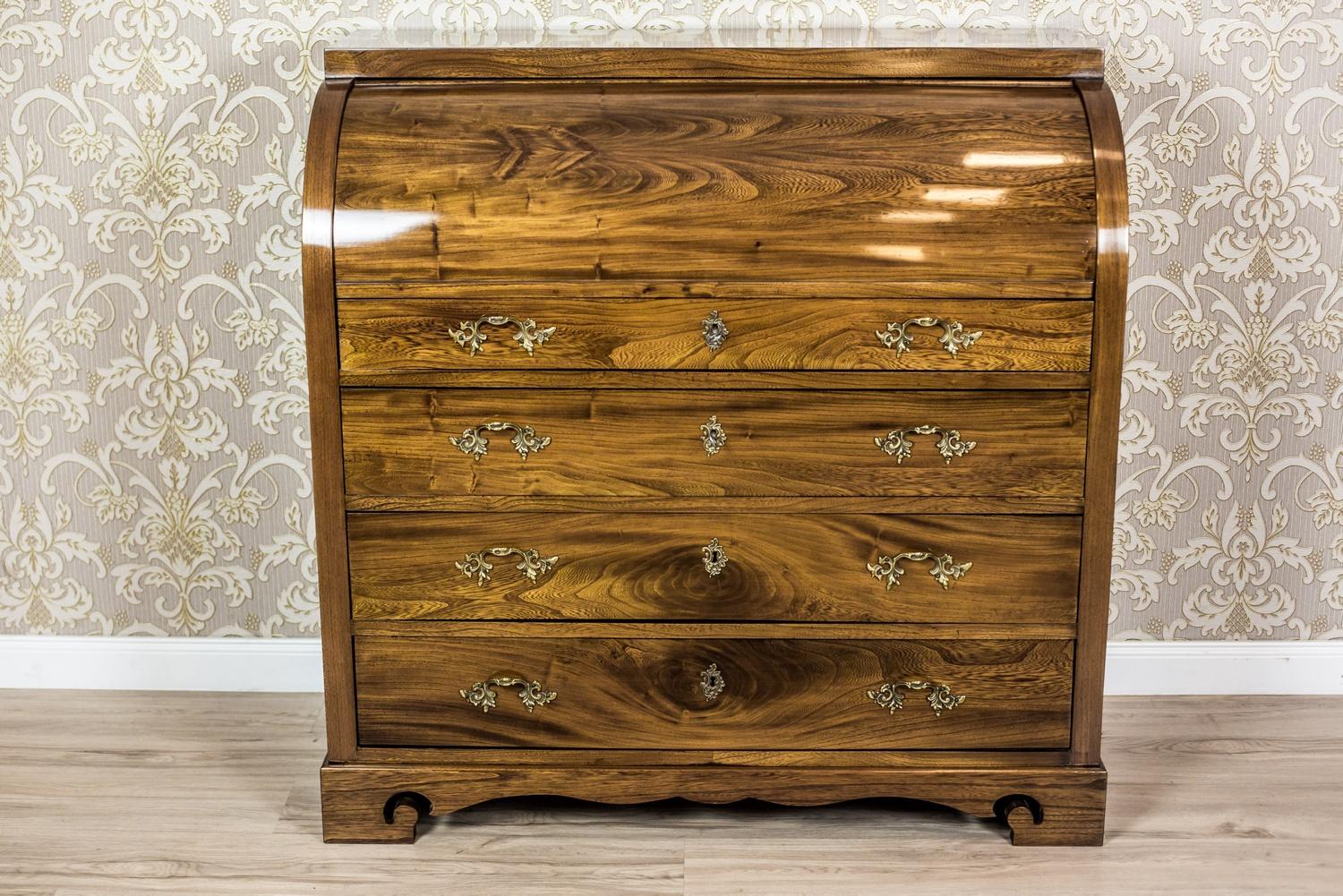 We present you this piece of furniture made of solid elm wood with a beautiful grain, circa 1840.
The chest section hides four drawers and a cylindrically closed lid; it is placed on a separate base.
The upper drawer of the secretary desk is