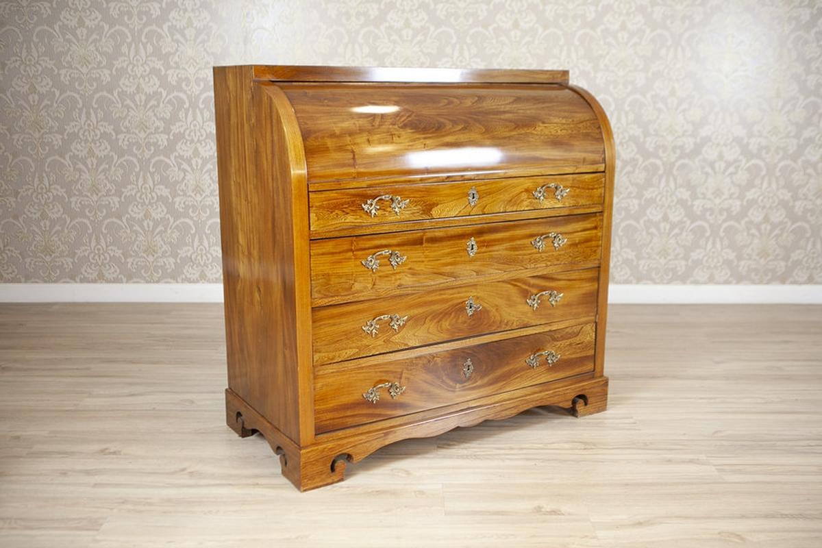 Secretario antiguo de madera de olmo de 1840

Este exquisito escritorio de secretaria antiguo con tablero enrollable desprende una elegancia atemporal con sus ricas y cálidas vetas de madera y su intrincada artesanía. La pieza cuenta con un