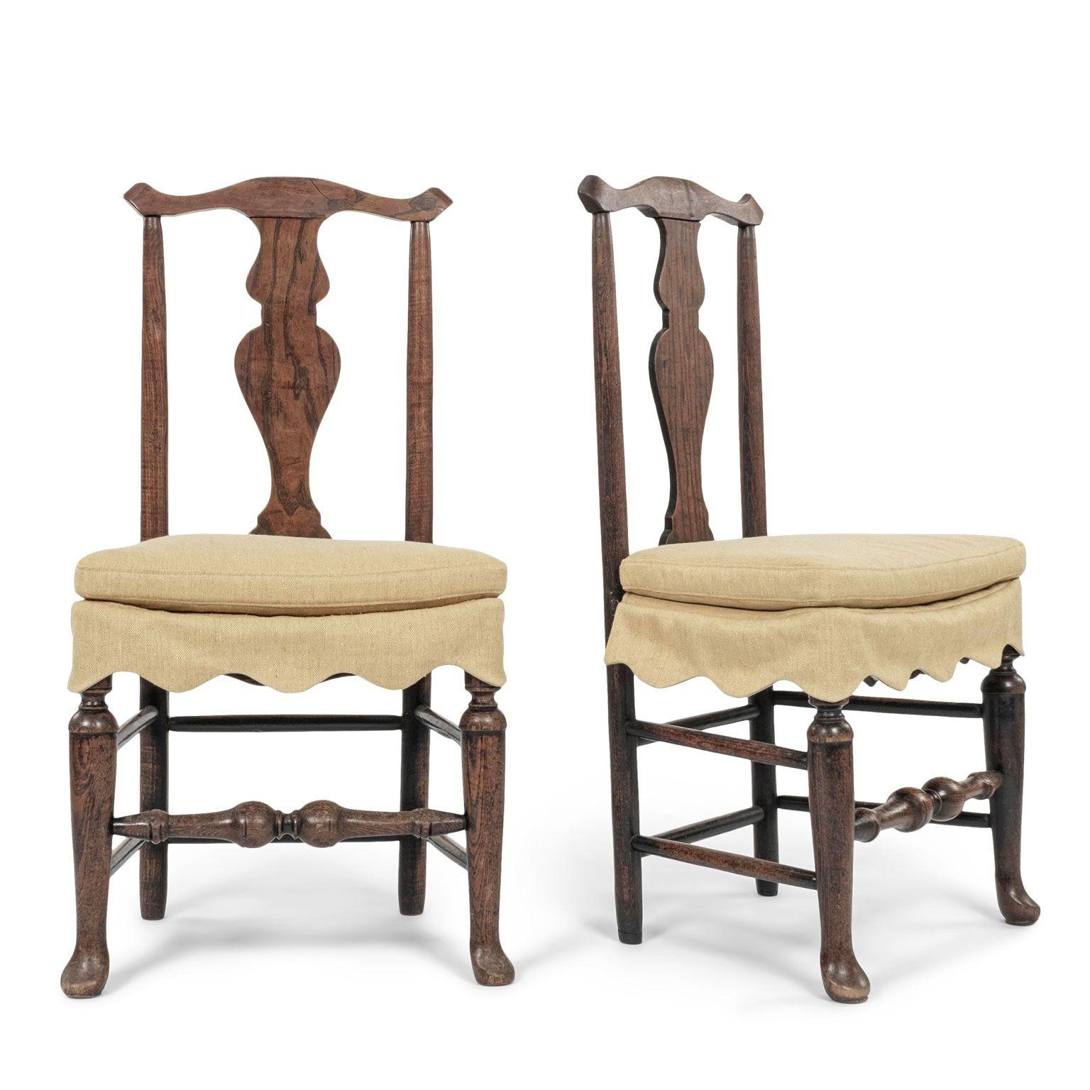 Pair of elm side chairs dressed in mustard-color linen skirts. English country side chairs hand-carved from elm wood in Queen Anne style circa 1750-1779. Beautiful wood grain and brown color. Sturdy, stable with no wobble. Newly dressed in