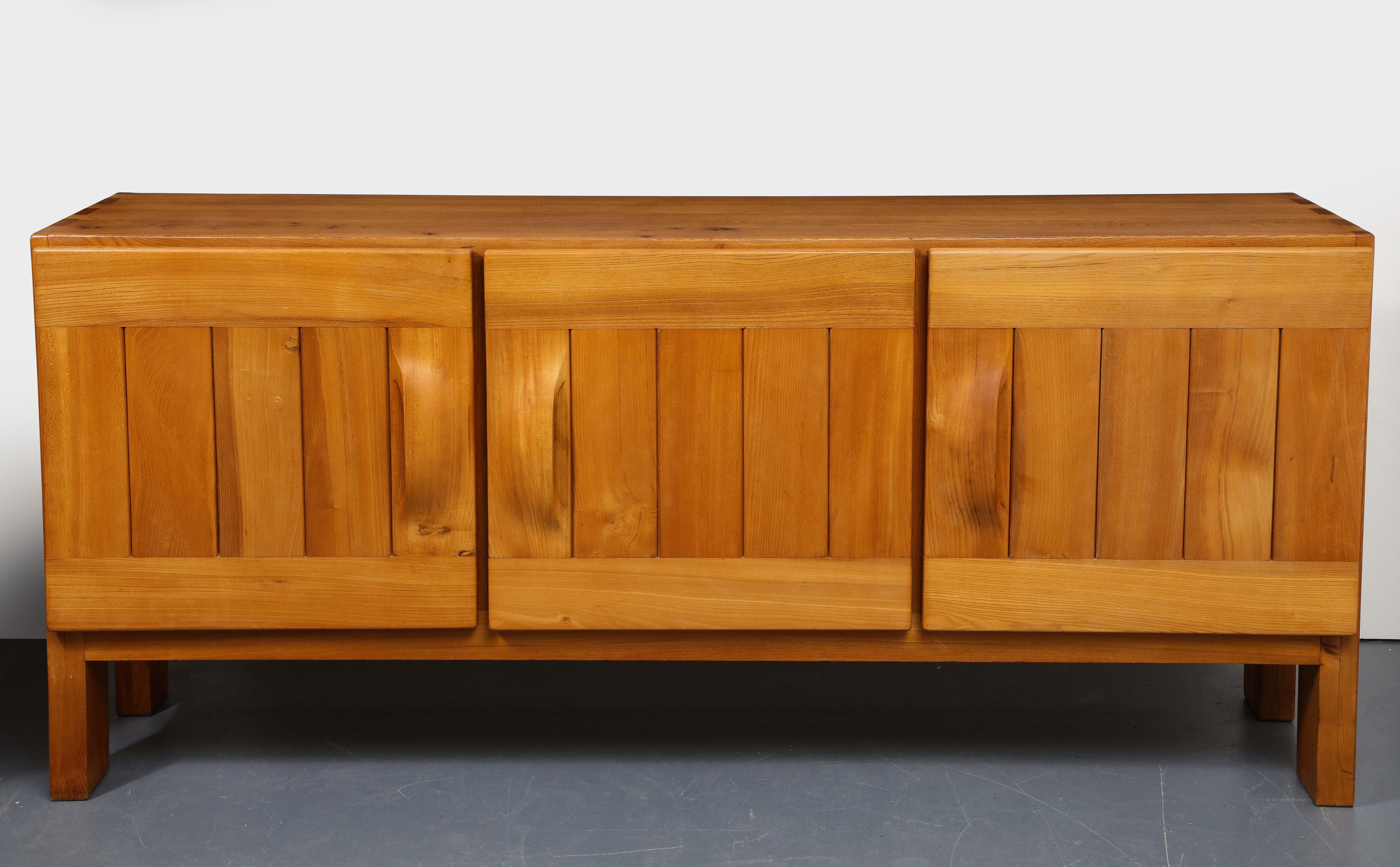 Elm Sideboard by Maison Regain, France, circa 1960s. 

This simple yet highly sophisticated sideboard consists of a solid elm construction, plank legs, and vertically-paneled doors with organically rounded, hand-carved handles. 

Excellent