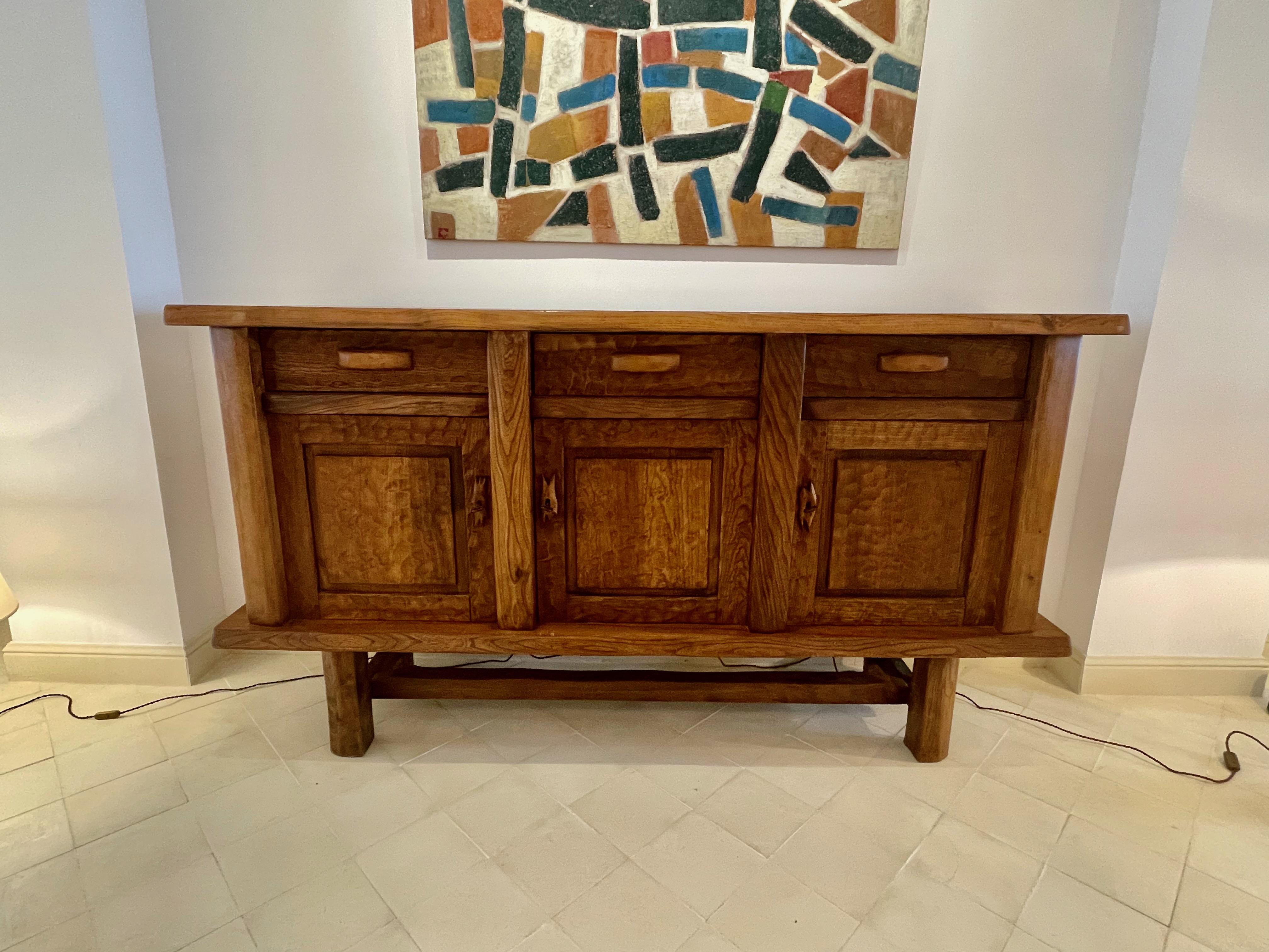 1960's Danish brutalist design credenza.
Decorative carved panels and three front doors and three front drawers.
Smoothly carved border around entire top surface.
Raised and sits on top of trestle base.
Three interior shelves provide additional