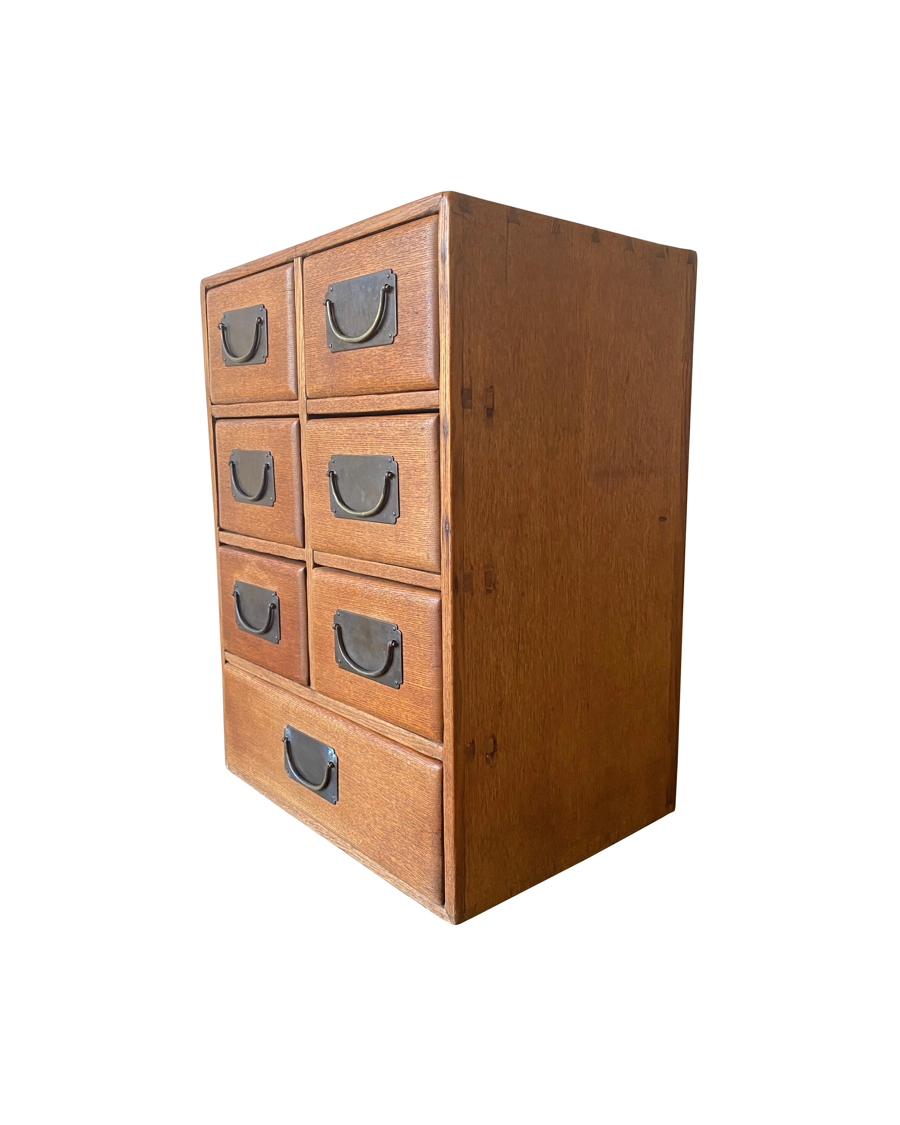 An early 20th century Elm wood lacquered Chinese cabinet featuring original fittings. This cabinet features a simple yet elegant shape and 7 drawers (6 smaller and 1 larger full width drawer at its base). There are some markings and scratches on the