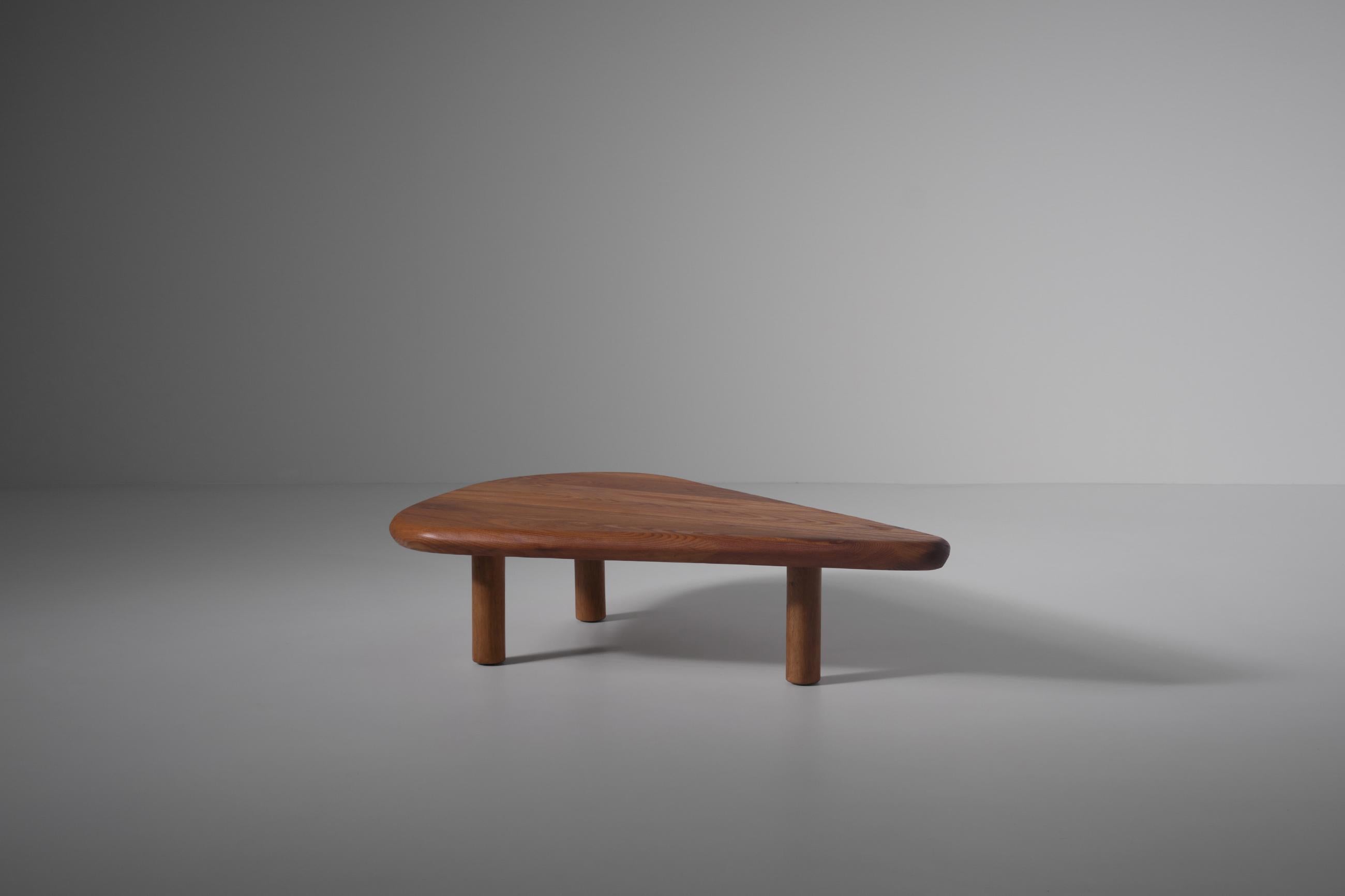 Solid Elm coffee table, France 1970s. Beautiful floating free form top made in solid warm colored Elm wood with a beautiful exposed grain. The 5,5 cm thick solid top has a nicely shaped edge and stand on three cylindrical legs, giving it almost a