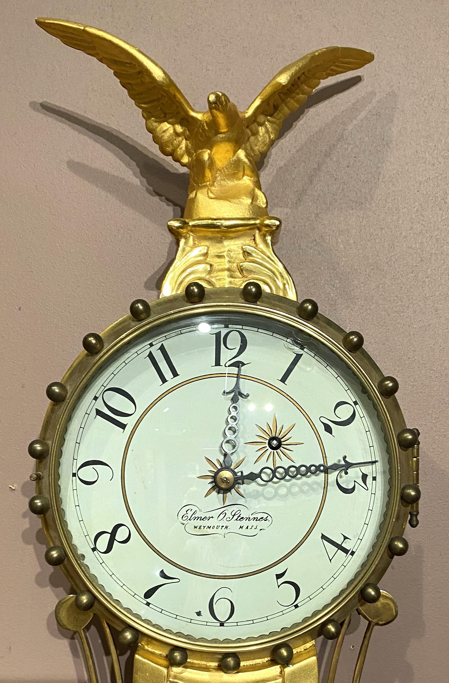 Une belle  exemple d'horloge girandole banjo faite à la main par le célèbre horloger de Weymouth, Massachusetts, Elmer O. Stennes (1911-1975), avec un cadran circulaire signé et un entourage de boules en laiton, surmonté d'un aigle sculpté et doré