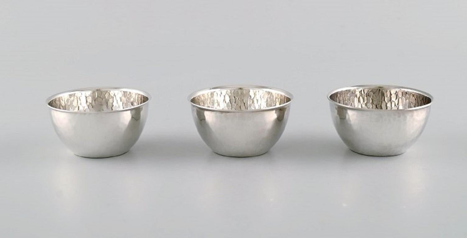 Elon Arenhill (1922-2018). Well-known Swedish silversmith. 
Twelve modernist cups in hammered sterling silver. 
Dated 1974.
Measures: 5.5 x 3 cm.
In excellent condition.
Stamped.
Our skilled Georg Jensen silversmith can polish all silver and