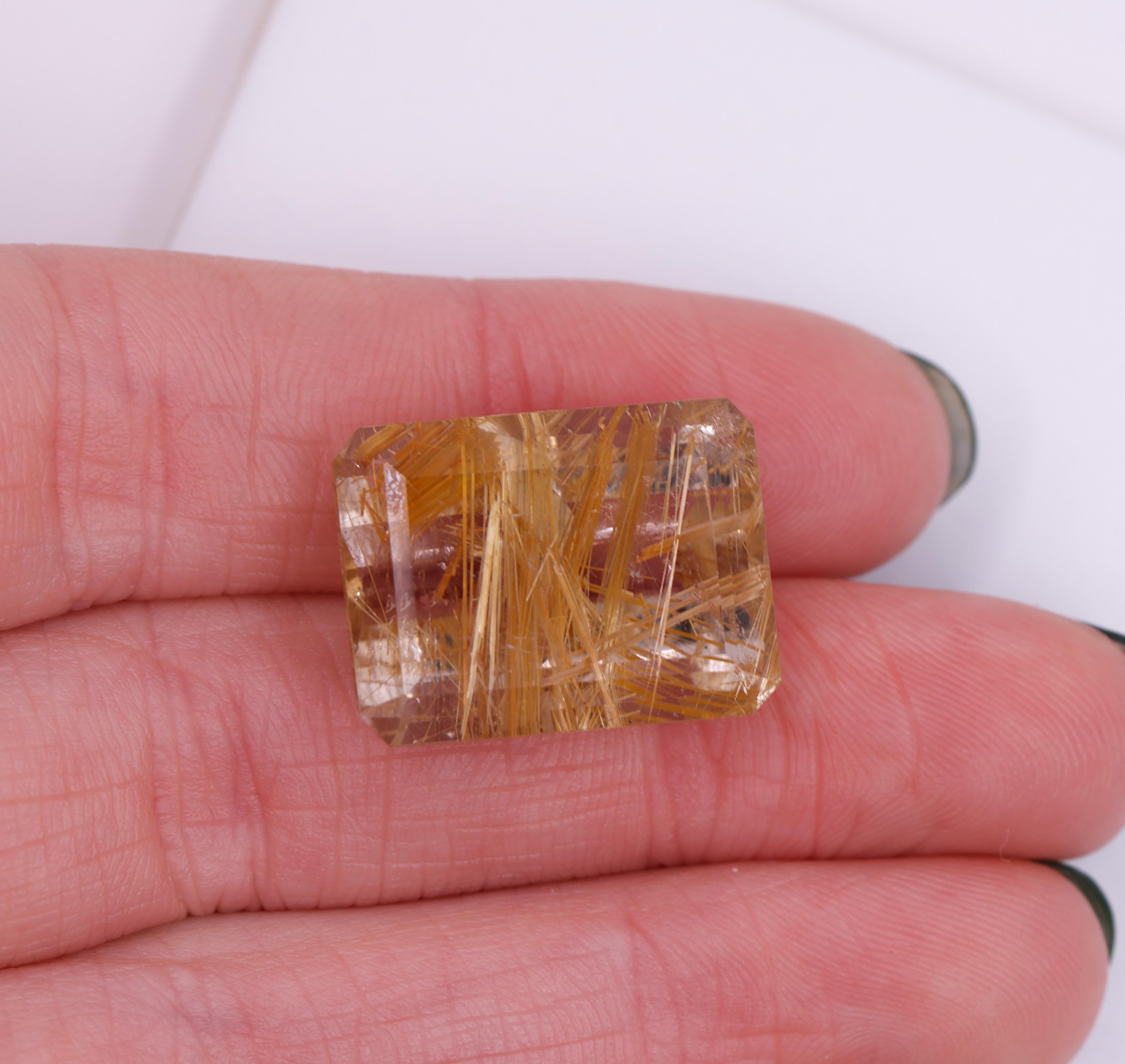 Presenting an elongated emerald cut 15.86 carat rutilated quartz loose gemstone! This gemstone exhibits a rectangular shape with precise facets that accenture it's clarity and brilliance. The rutile inclusions within the quartz create captivating