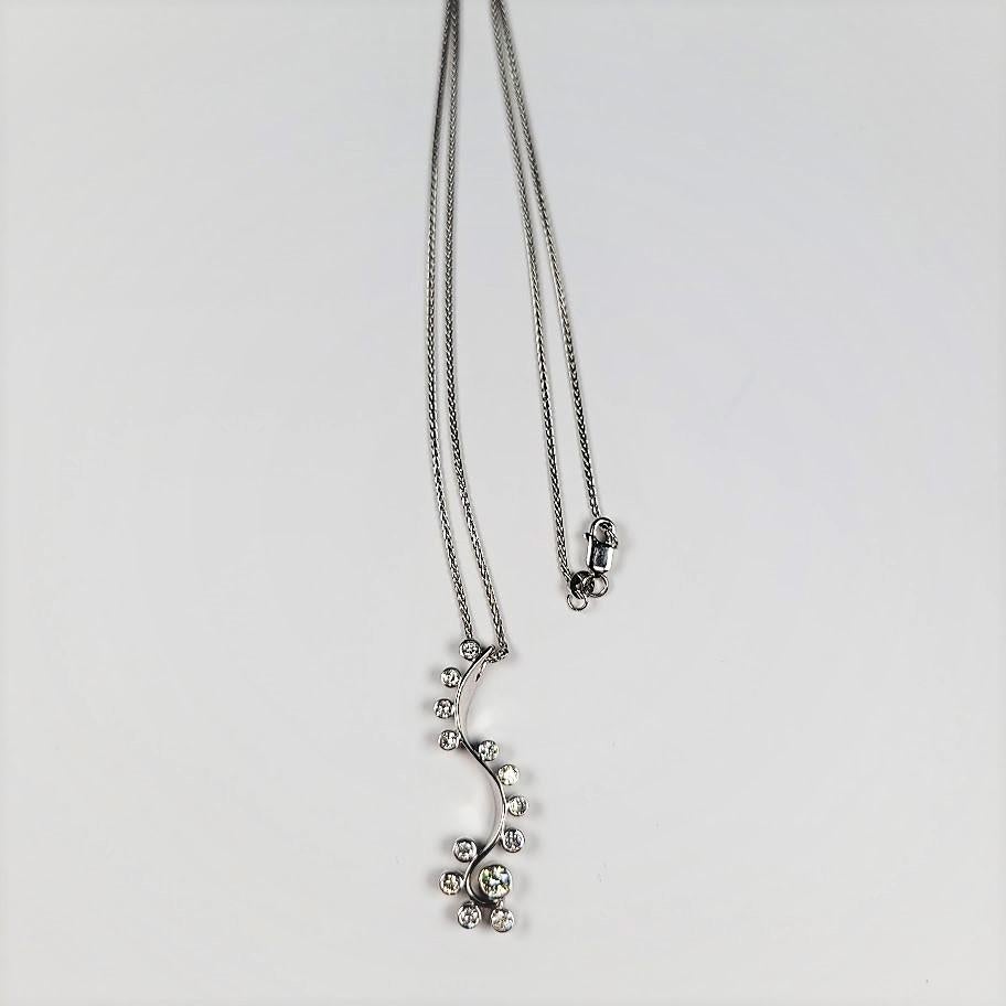 Composed of 14 karat white gold, this fun necklace supports 0.65 carats of bezel-set, diamonds.  The necklace is a total of 16