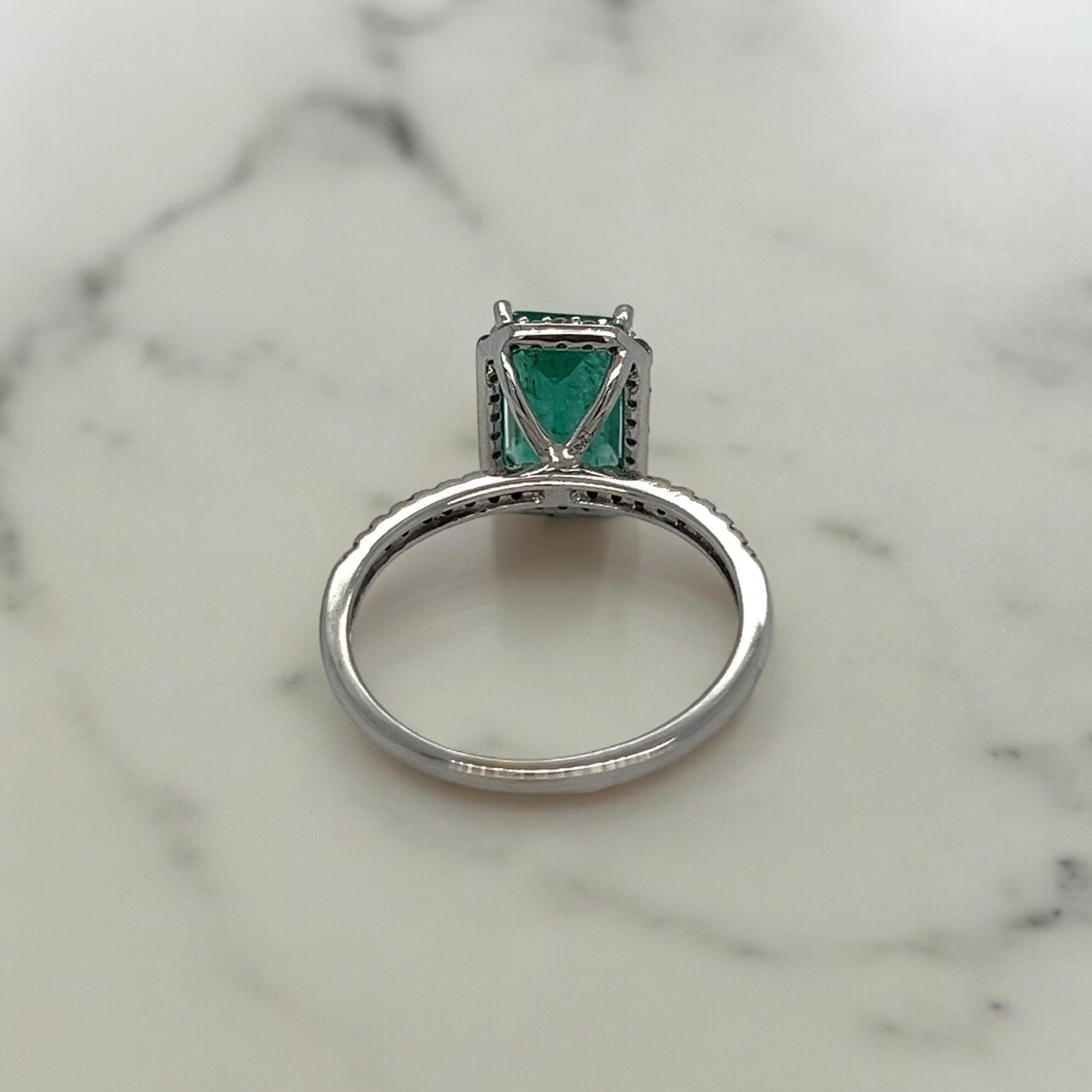 This gorgeous statement ring features a 1.81 carat emerald cut emerald center stone. The halo around the emerald and the band feature 0.40 total carats of round diamonds. Set in 14k white gold. Ring can be sized upon purchase.