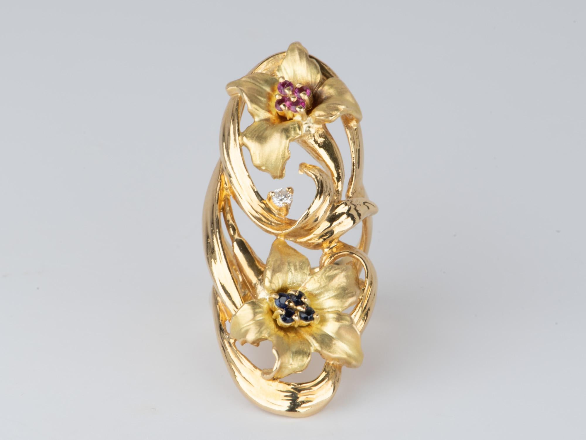 Make a statement with this bold, 18K gold navette-style ring, featuring a vibrant elongated floral design and clusters of rubies, sapphires, and diamonds. The elongated design and heavy gold allows the ring to hug your finger so nicely. Be the envy