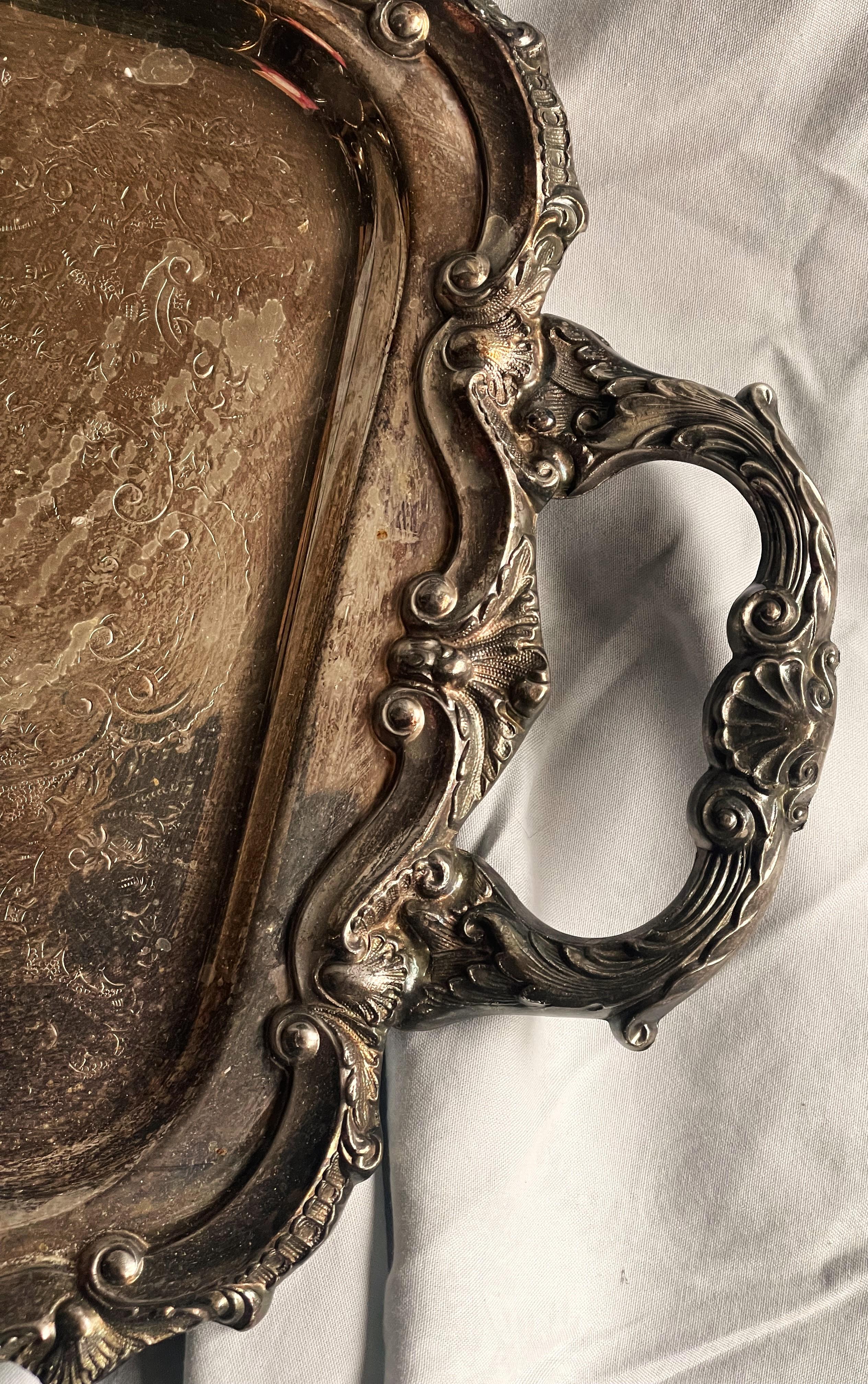 Here is a beautiful, heavy fine quality silverplate elongated tray with lovely raised swirl design around the entire edge and a beautiful embossed pattern on the handles that is topped with a shell, even the underneath of the handles has a pattern.
