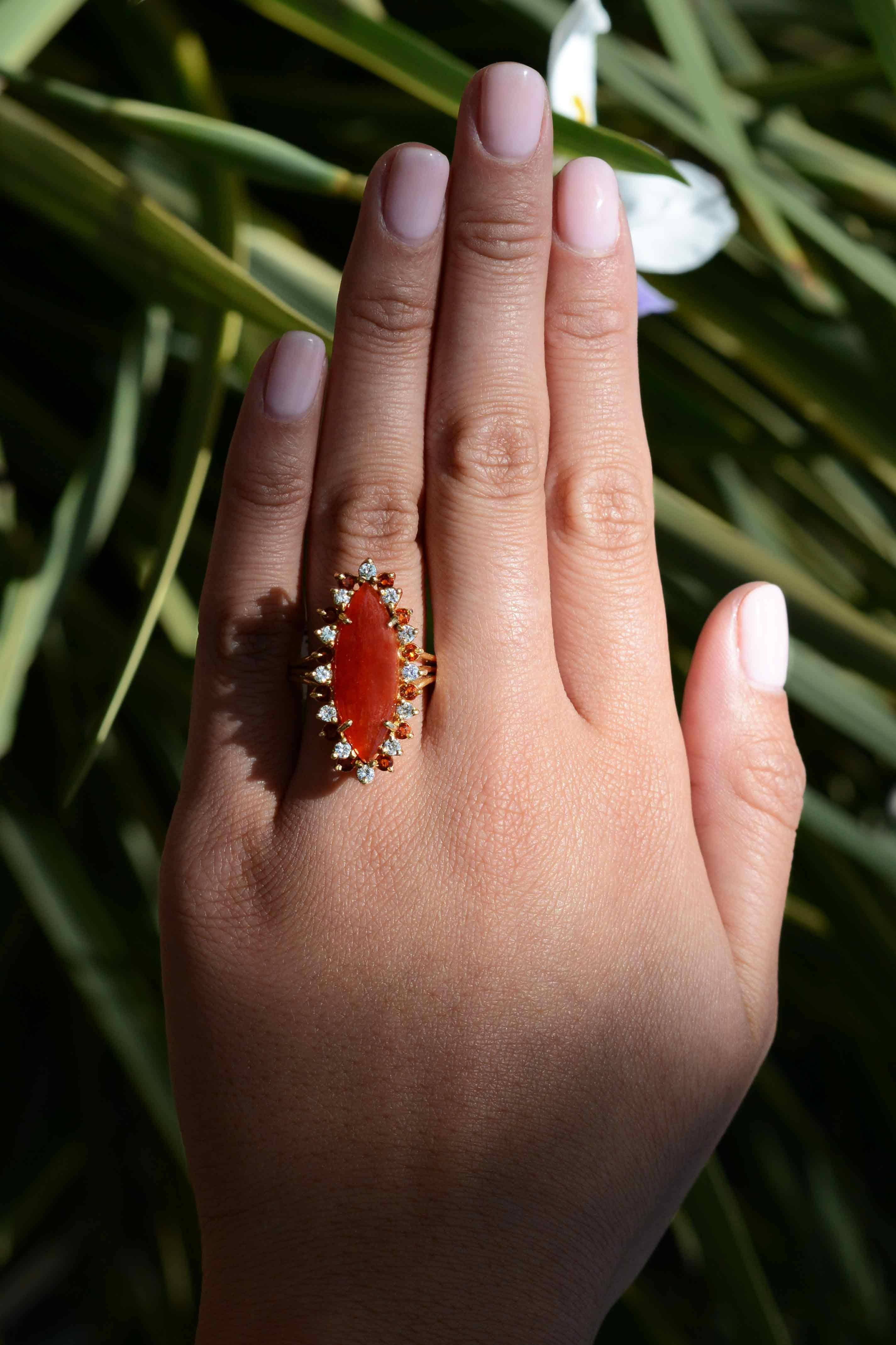 A fiery and affordable cocktail ring with a sizable carnelian showcased as the center gemstone. This red/orange gem, is worn for good luck, courage and strength. The surrounding halo alternates with elevated bright white diamonds and recessed vivid,