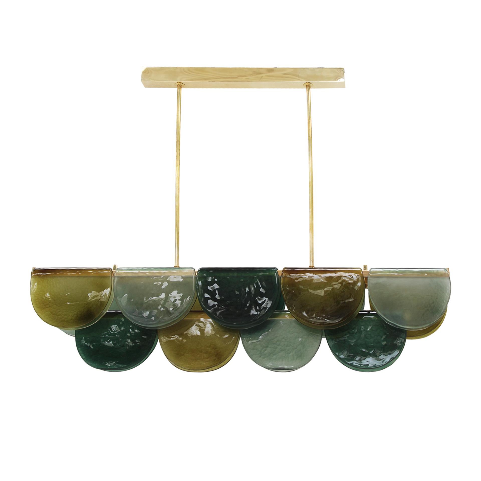 Lámpara colgante alargada compuesta por una estructura de latón de tres niveles, iluminada por tiras de LED que recorren toda su longitud. Cada nivel está envuelto con una placa de cristal de Murano, creando un efecto plegado alrededor de la