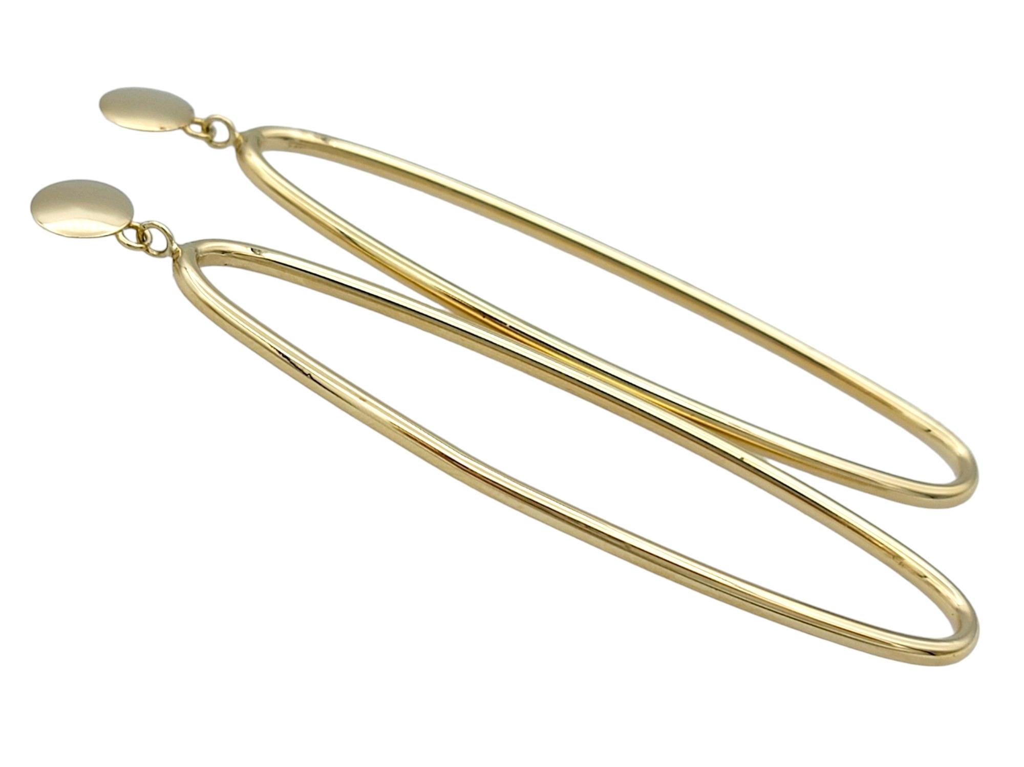 Questo splendido paio di eleganti orecchini pendenti è splendidamente incastonato in oro giallo 14 carati. Questa sofisticata coppia è caratterizzata da un elegante design ovale allungato che aggiunge un tocco di moderna eleganza e fluidità a