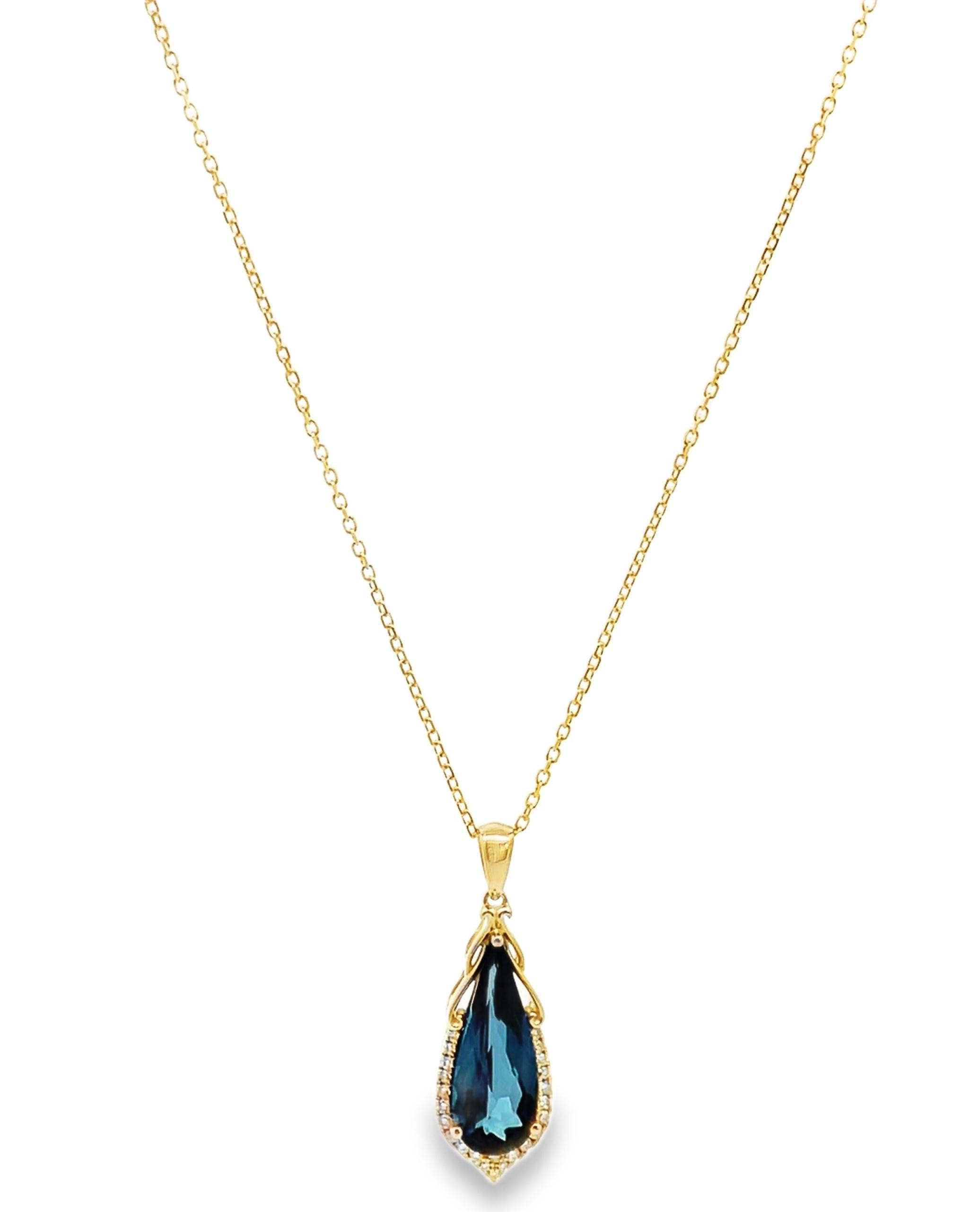 Pendente in oro giallo 14K con 24 diamanti rotondi per un peso totale di 0,15 carati.  Al centro un topazio blu a forma di pera del peso di 3,92 carati. Il ciondolo scorre su una catena in oro giallo 14K da 20 pollici.
