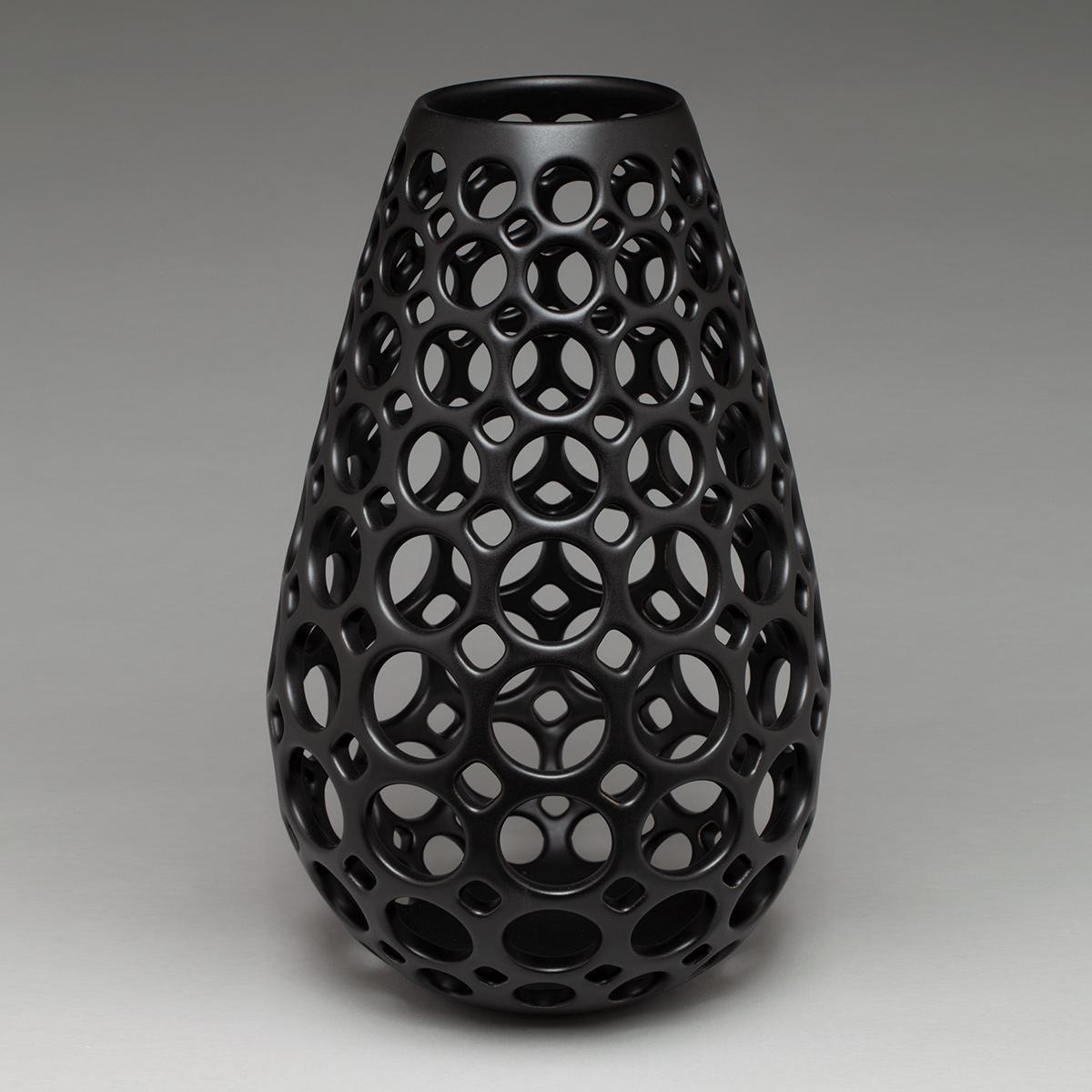 Inspired by Mid-Century Modern design, this piece is wheel thrown and hand pierced stoneware with a black satin glaze. Small holes are created when the clay is still wet and then each hole is painstakingly enlarged and smoothed when the clay is bone