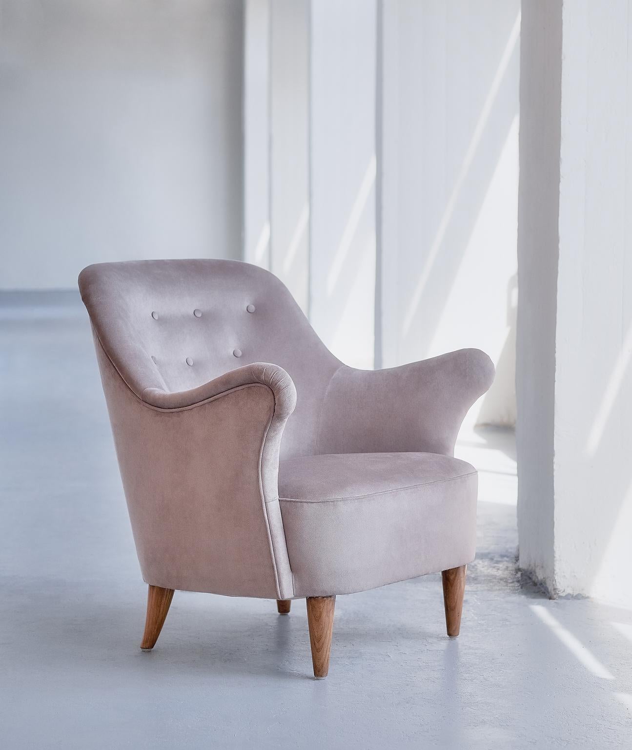 This rare armchair was produced by AB Elsa Gullberg in the late 1930s. The organically shaped arms of the chair and the carved, tapered legs give the chair a sculptural and modern feel. The chair is upholstered in a taupe/grayish velvet fabric, the