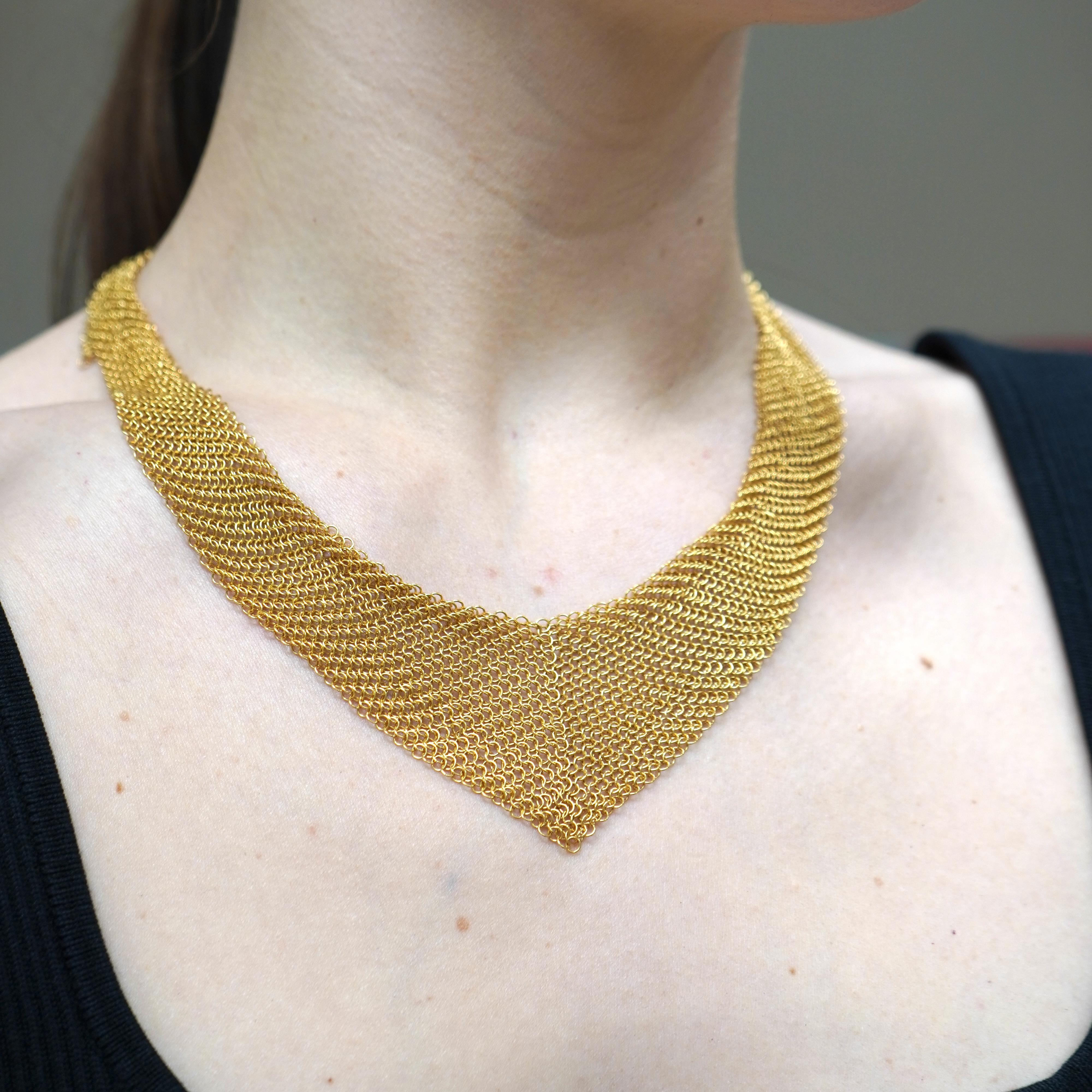This vintage Elsa Peretti necklace for Tiffany & Co. from the 1990s features a striking mesh chain mail design crafted in 18k gold. The flexible mesh construction drapes elegantly around the neck, creating a fluid, sculptural silhouette that