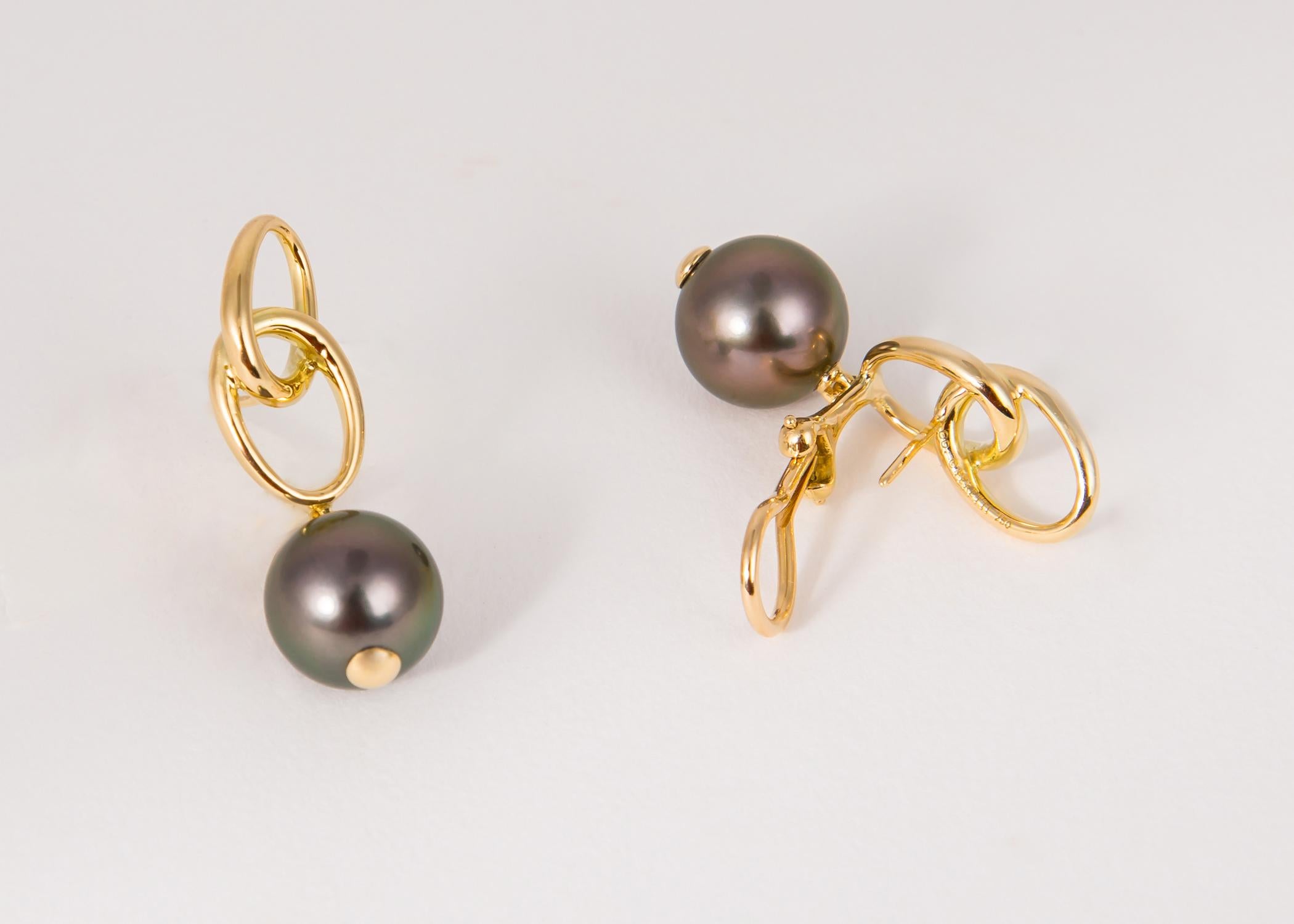 Elsa Peretti a toujours prouvé que moins est plus. De riches perles de Tahiti sont suspendues sous d'élégantes boucles géométriques. 1 1/4 pouces de longueur  Les perles font 10,6 mm chacune. 