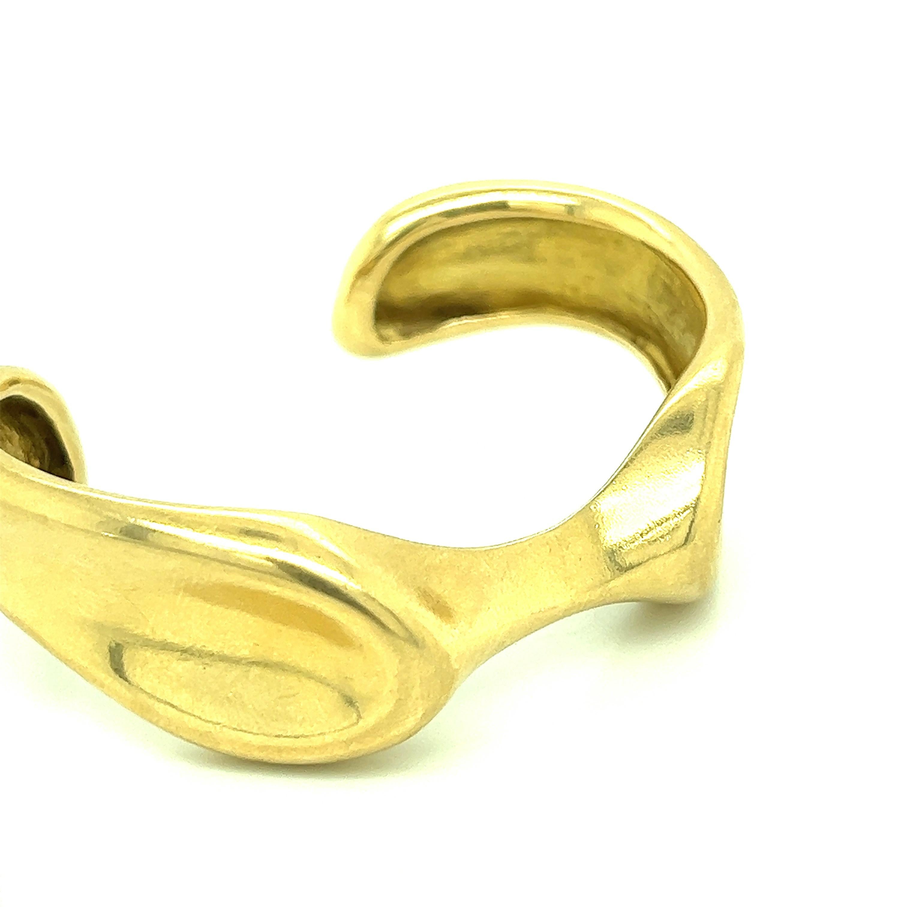 Elsa Peretti for Tiffany & Co. 18 karat yellow gold bangle. Marked: Tiffany & Co. / 18k / Peretti. Inner circumference: 6.25 inches. Total weight: 53.7 grams. Width: 2.63 inches. Length: 2 inches. 