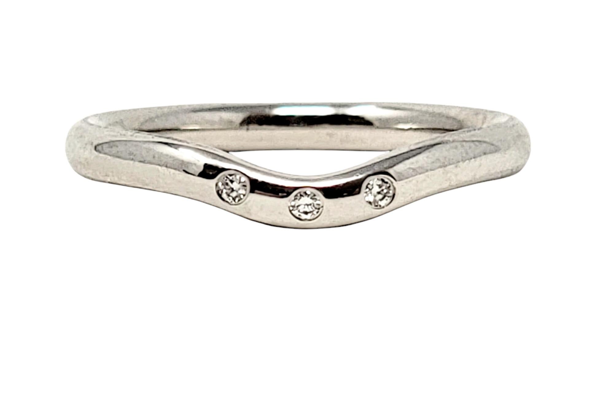 Ring size: 5

Beautiful contemporary wedding band ring by Elsa Peretti for Tiffany & Co.. This sculptural piece features 3 small round diamonds at the center, where the band curves slightly to accommodate an engagement ring. The perfect addition to