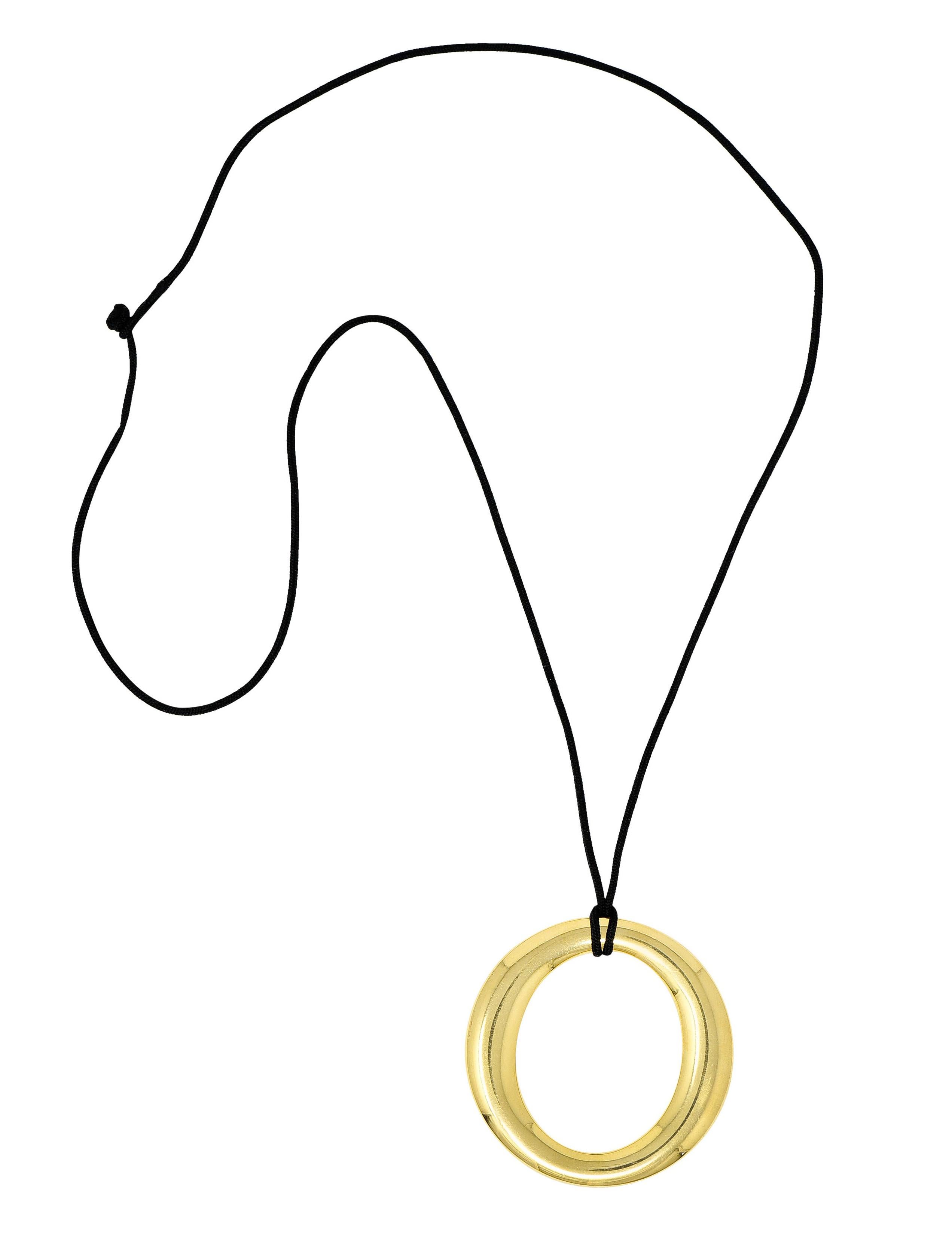 Substantial pendant is designed as a slight ellipse form

With an open center and a brightly polished finish

Suspending from a black silk cord

Stamped 750 for 18 karat gold

Fully signed Elsa Peretti Tiffany & Co. Spain

Circa: 1990s

Length: 25