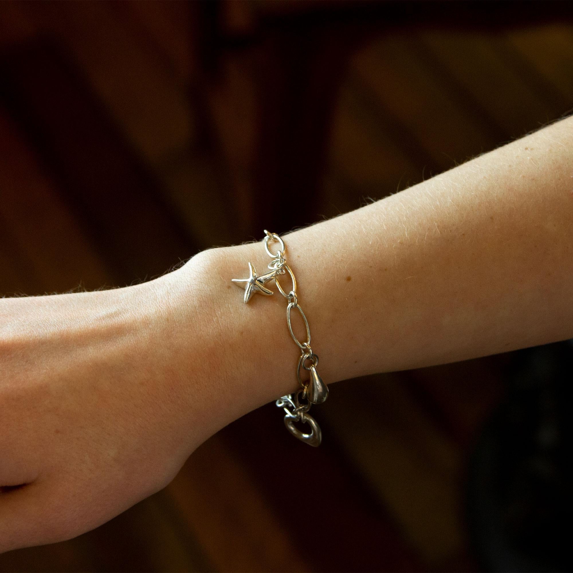 Ce bracelet à breloques iconique a été conçu pour Tiffany & Co. par l'une de ses créatrices les plus prolifiques et les plus appréciées, Elsa Peretti, dans les années 1980. Fabriquée en argent sterling, la chaîne ovale à maillons présente les motifs