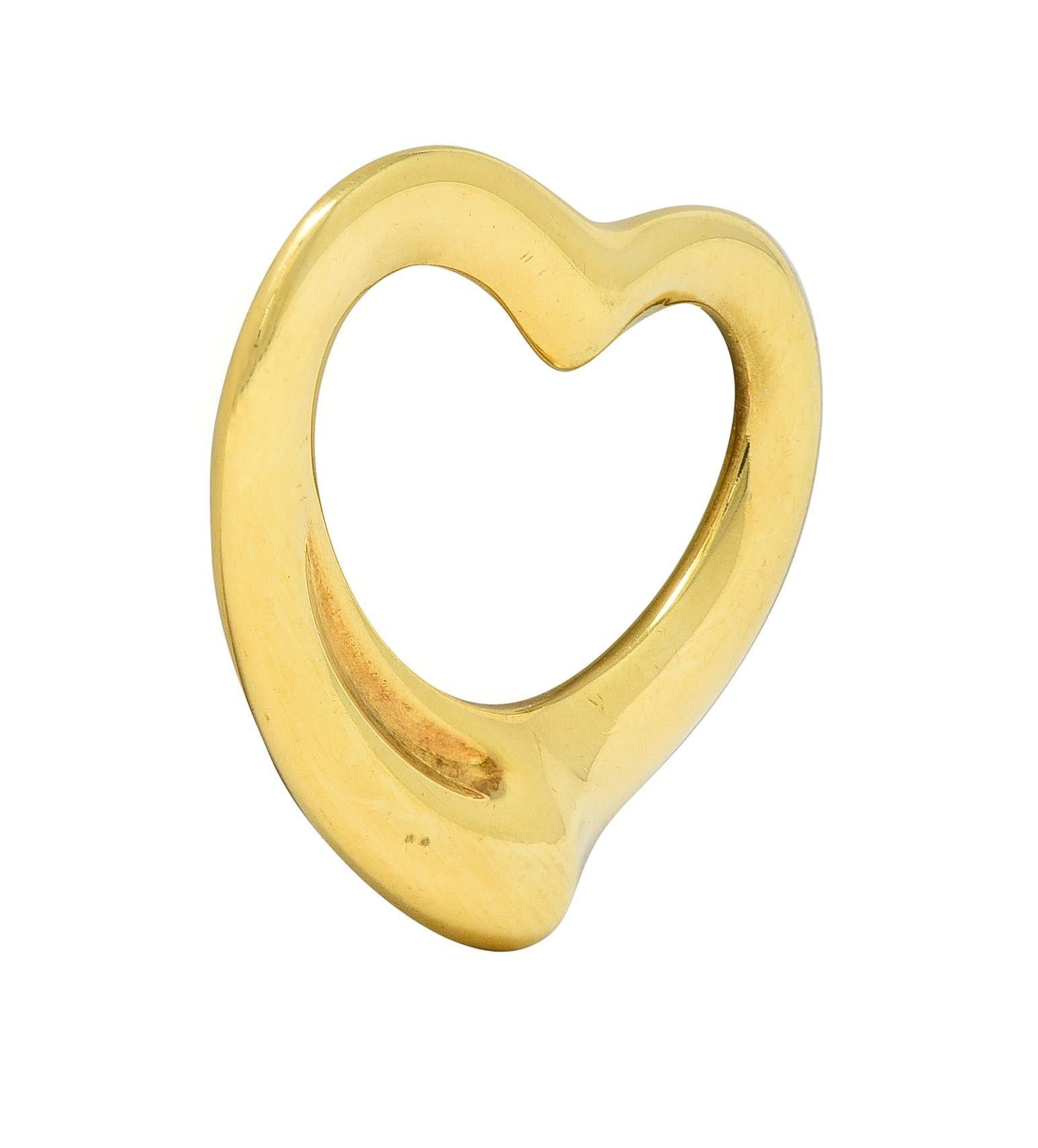 Designed as a sinuous yellow gold heart 
With pierced center and organic edges
With high polish finish
Stamped for 18 karat gold
Fully signed for Tiffany & Co. Elsa Peretti, Spain
Circa: 2000s; from the Open Heart Collection
Measures: 3/4 x 7/8