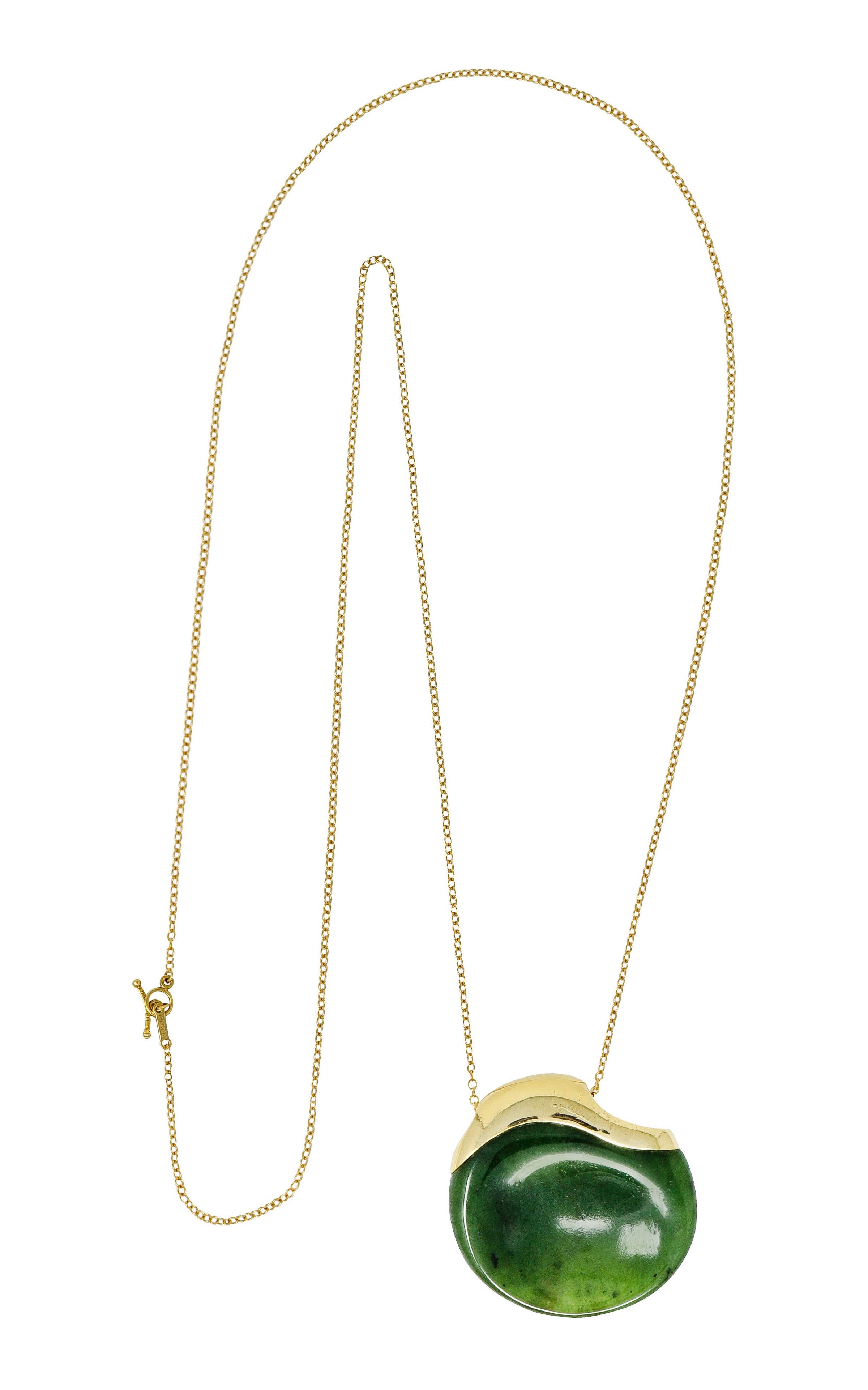 Pendant is comprised of nephrite jade and designed as a touchstone with a circular organic form with a concave center

Nephrite jade is finely polished and a translucent moss green mottled with intriguing black inclusions

Form is topped by high