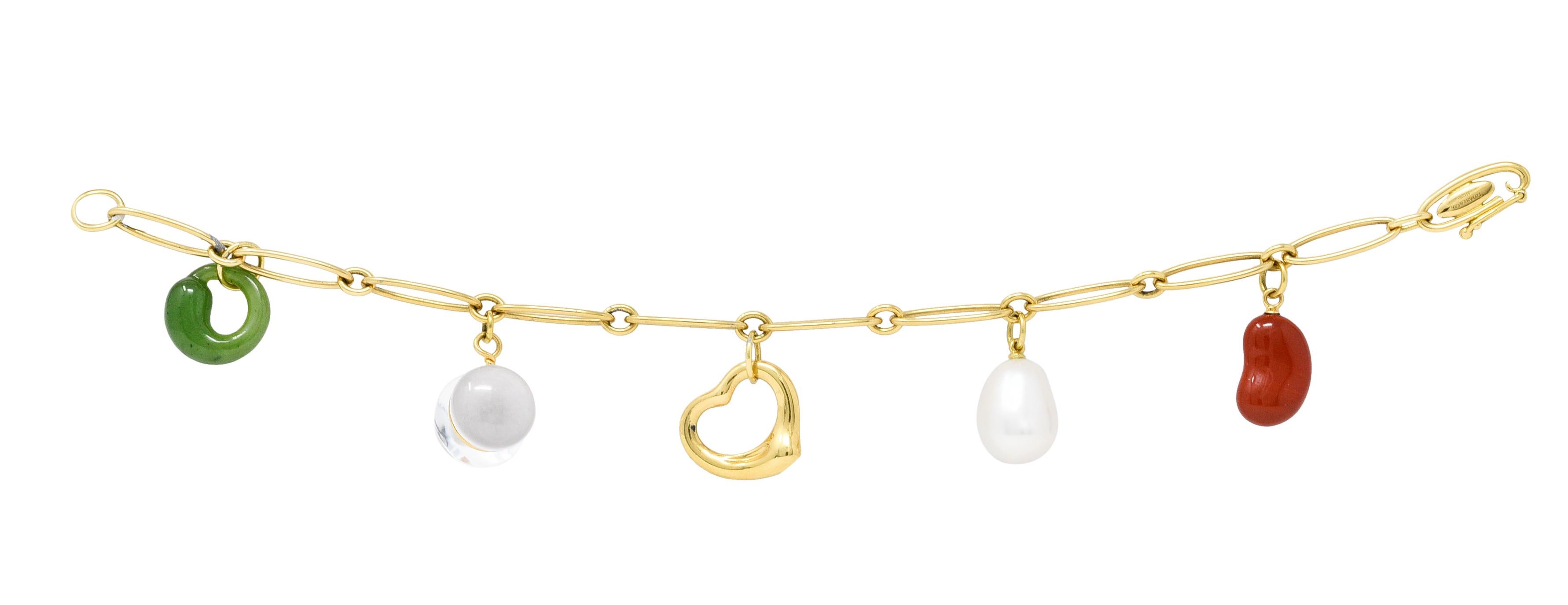 Bracelet is comprised of elongated paperclip style links

Suspending five charms from Elsa Peretti's iconic collections

A green jade eternal circle, a rock crystal jar, a red agate bean, a pearl drop, and a polished gold open heart

Completed by a