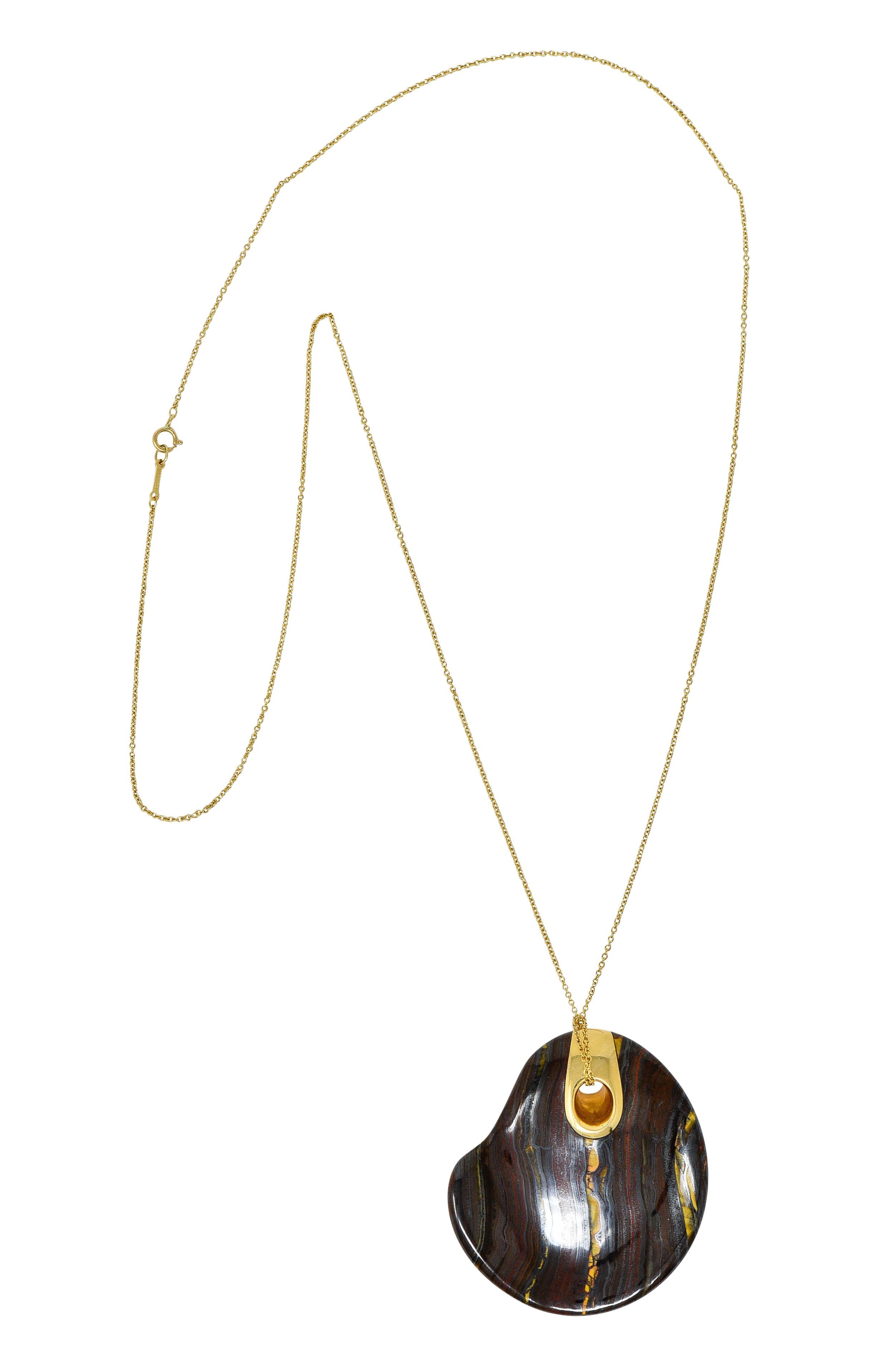 Pendant is comprised of tiger iron designed as a touchstone with an organic form and a concave center

Tiger iron is a striped and opaque aggregate found in Western Australia that features tiger's eye quartz, red jasper, and hematite

Topped by an