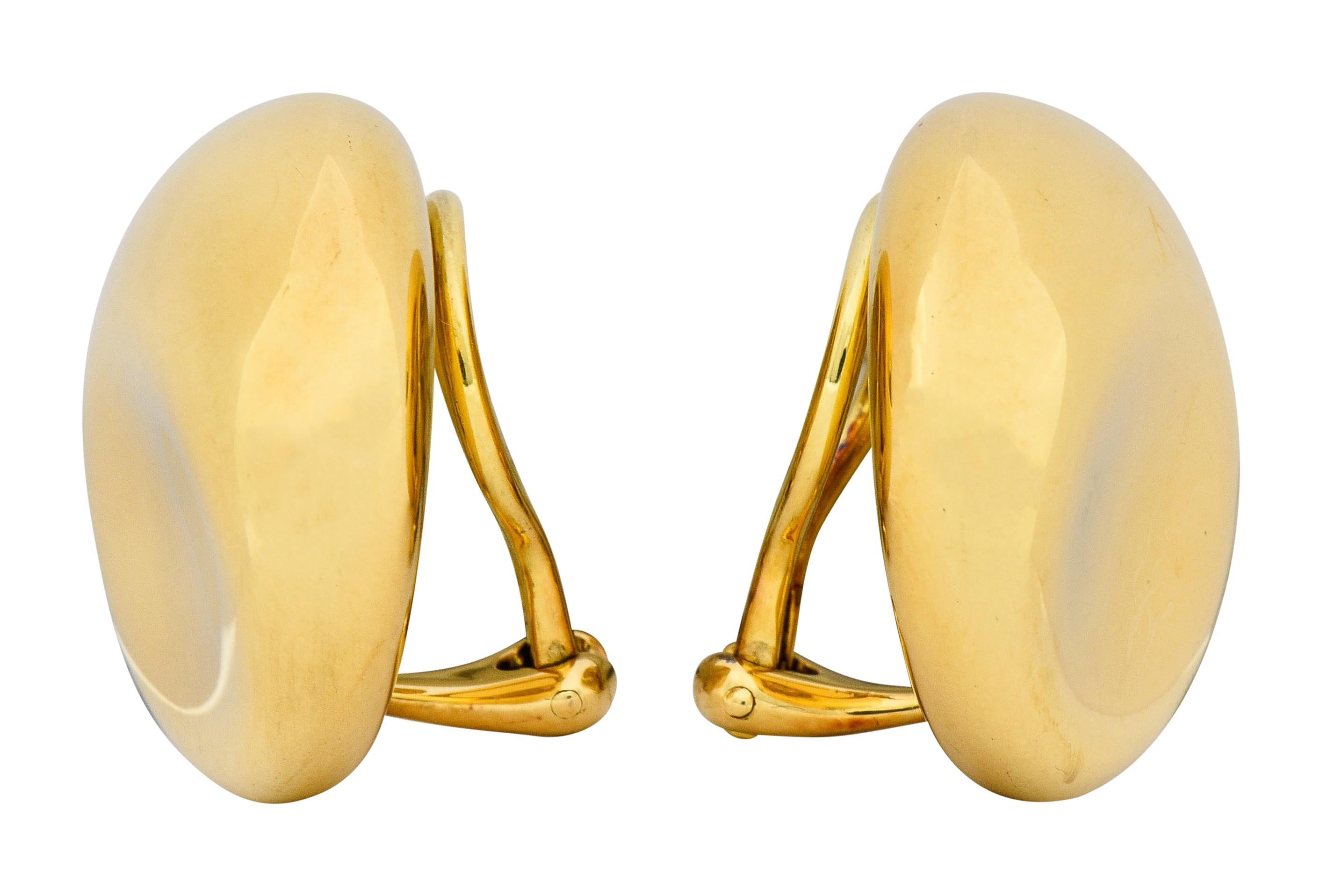 Ear-clips are designed as circular forms with a slightly concave indentation

With a high polished finish

Completed by hinged omega backs

Fully signed Elsa Peretti Tiffany & Co. Spain

Stamped 750 for 18 karat gold

Circa: 1980s

Measures: 7/8 x 1