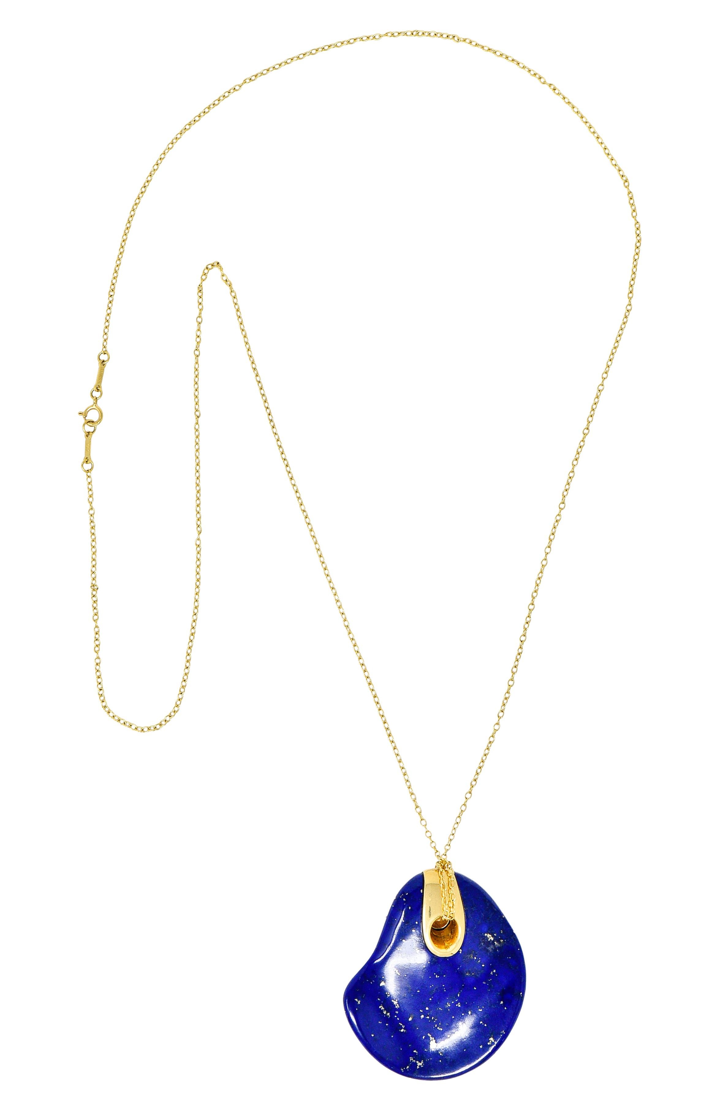 Necklace features a substantial and organically shaped lapis lazuli pendant. Opaque ultramarine blue in color with pyrite flecking. With chain wrapped through a pierced bale and gold surround. Stamped 750 for 18 karat gold. Fully signed Peretti