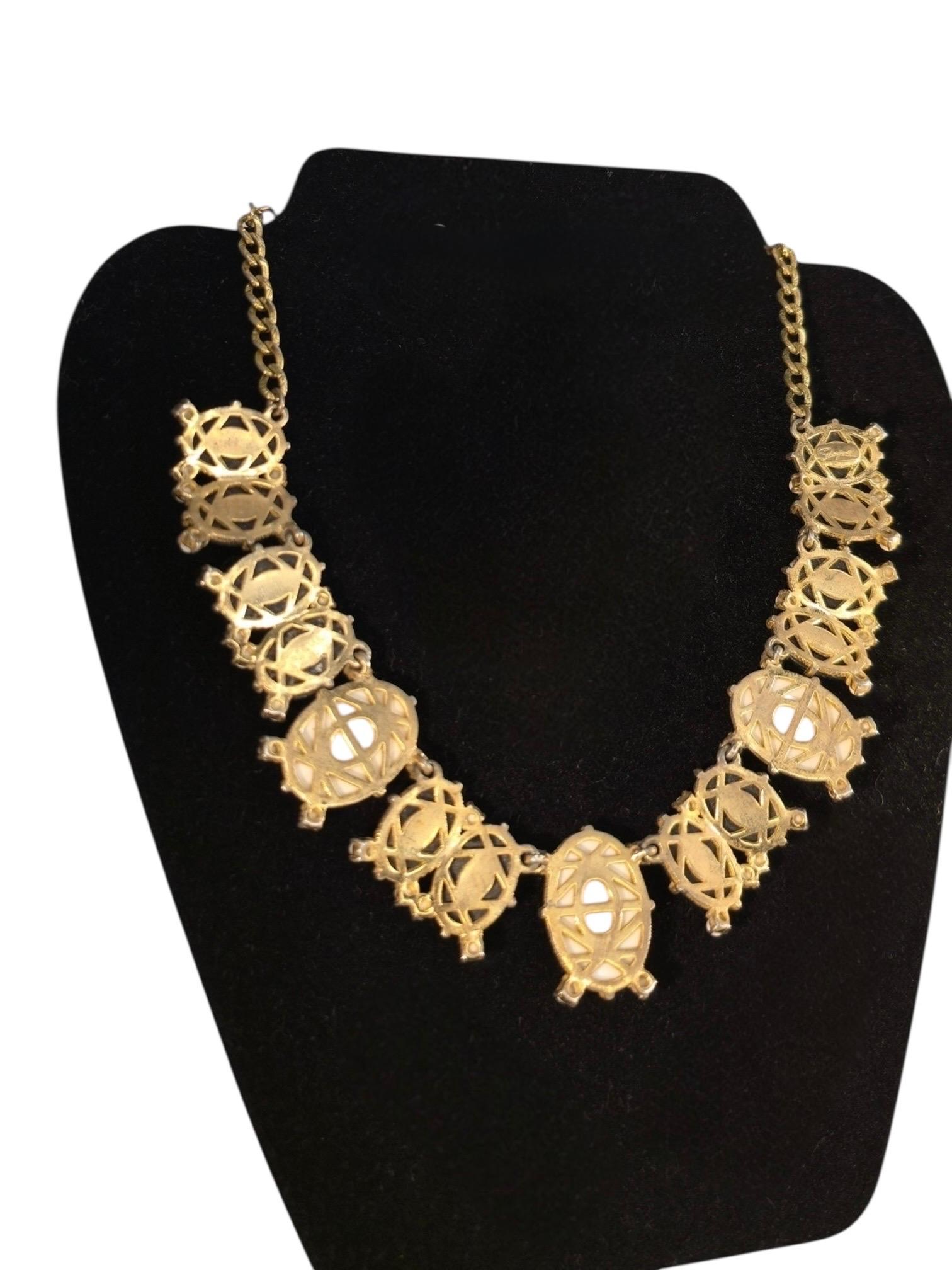A striking piece of mid-century costume jewelry from the legendary Elsa Schiaparelli, this 1950s statement necklace captures the surrealist flair and sculptural elegance that define the designer’s aesthetic. Crafted in a rich gold-tone setting, the