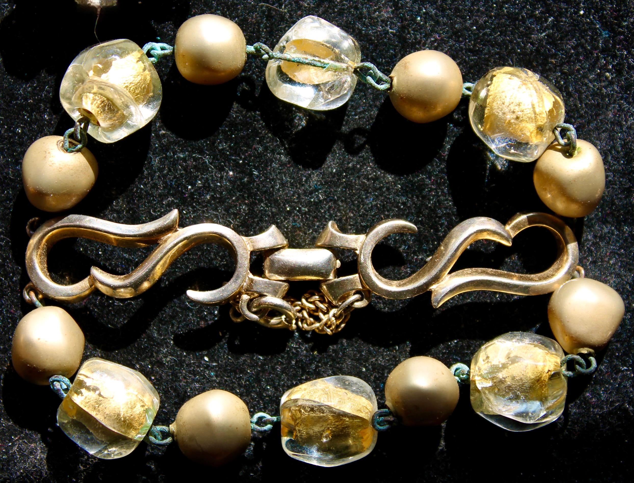 Pebble shaped clear crystal over gold nuggets connected 
with smaller matte gold pebble shaped beads- all out of a resin material.  Safety clasp with mirroring arabesque shaped connections. Length 7 1/4