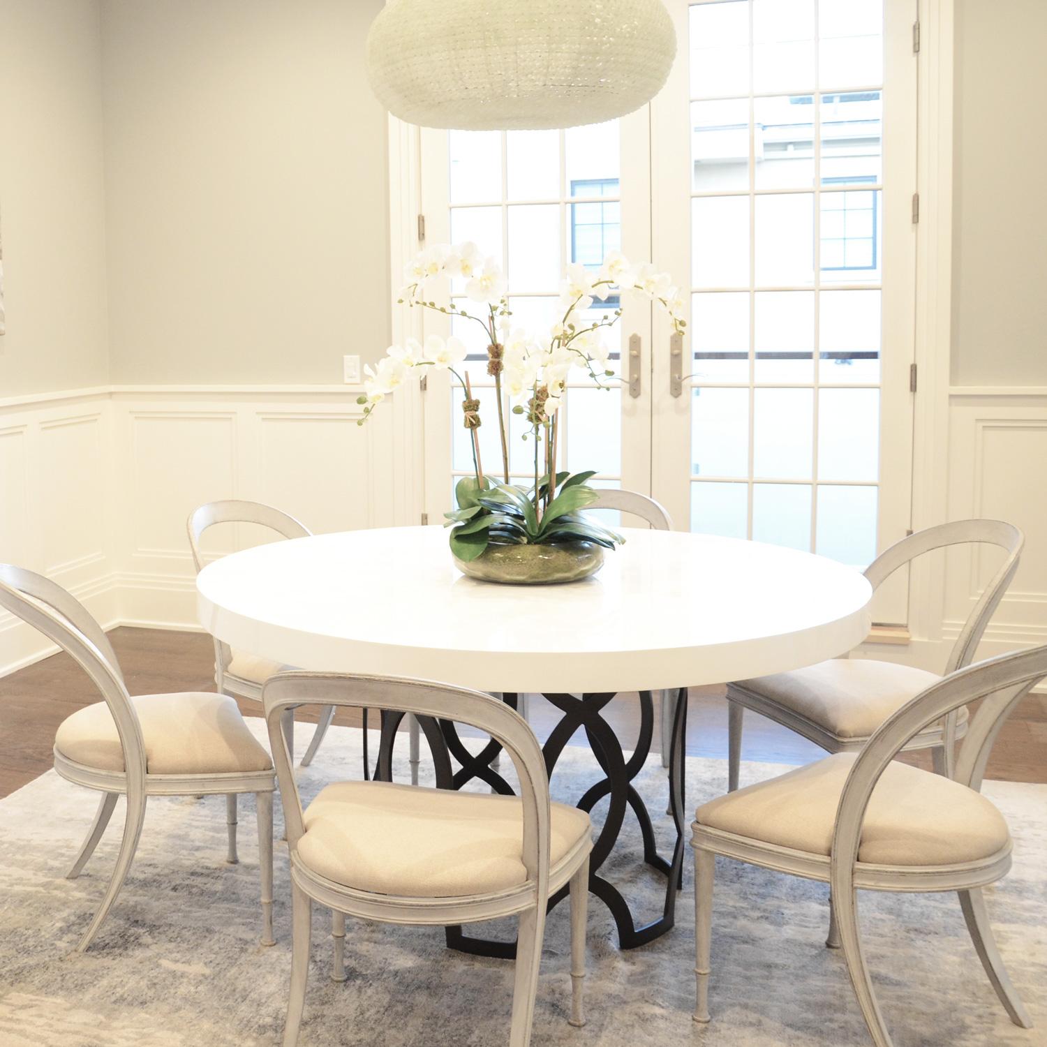 Round dining table with a handmade metal base. White lacquered wooden round top.
 