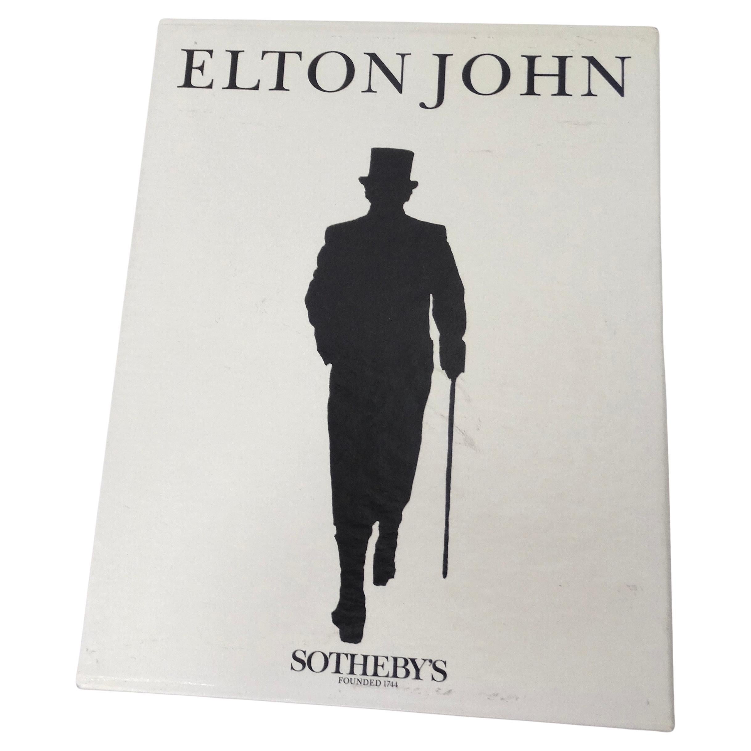 Mode und Musik kollidieren in dieser seltenen 1988 Sotheby's Elton John's Buchsammlung! Tauchen Sie ein in die Modegeschichte der Rocklegende Elton John mit dieser erstaunlichen Sammlung von Büchern, die detailliert auf die Kostüme, den Schmuck, die