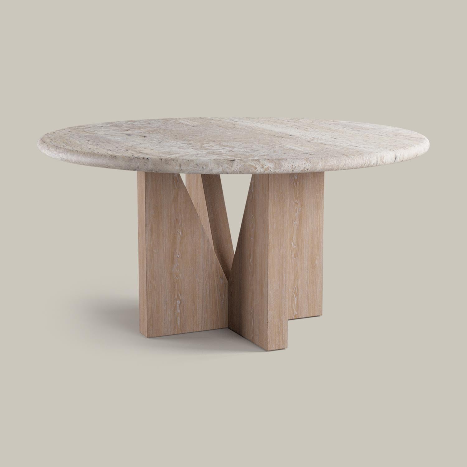 A honed natural travertine surface rests atop an angular cerused European oak base to form a clean, minimalist dining table. The sculptural opening allows air and light to flow through the base.